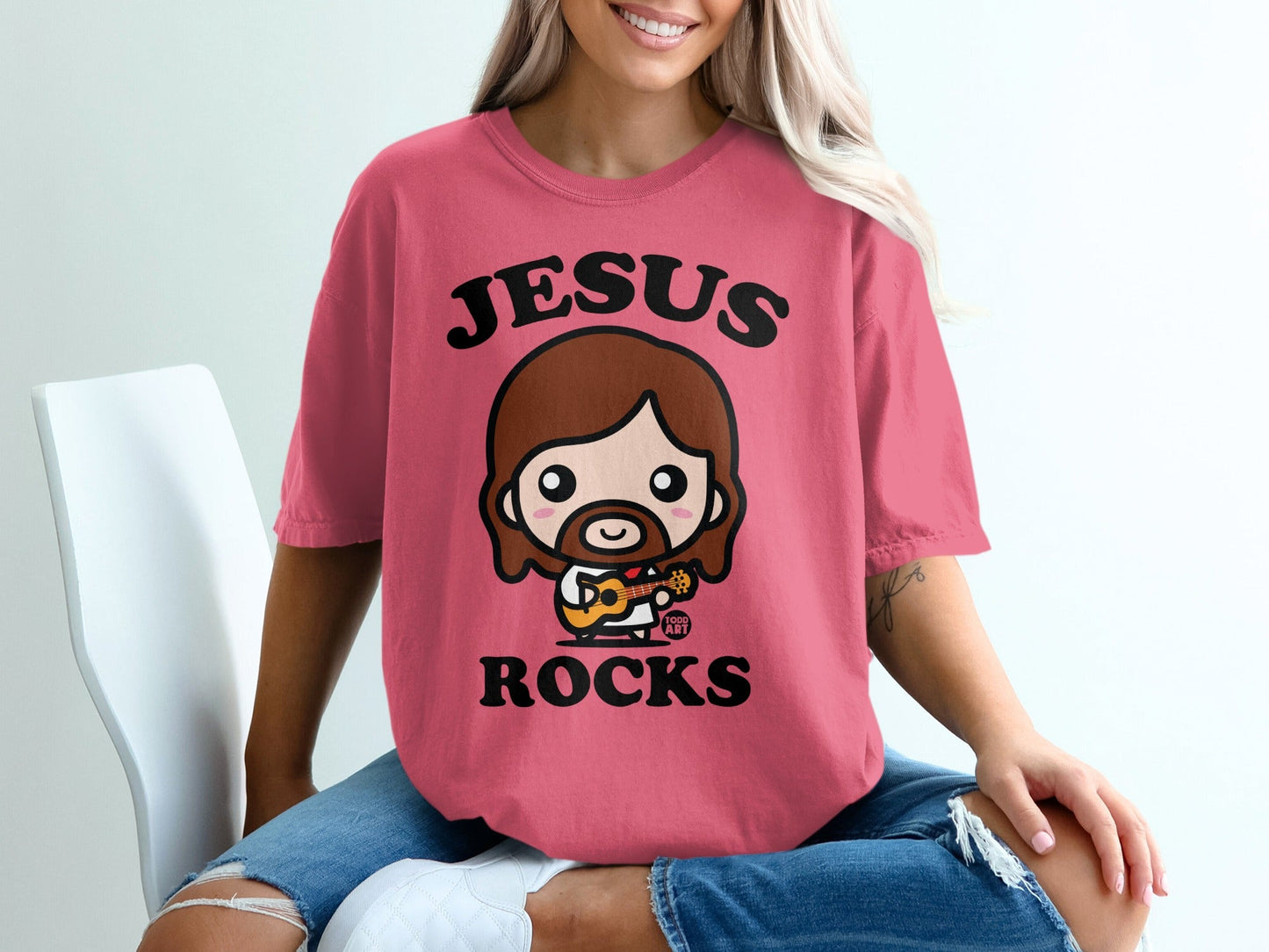 Pink t-shirt with "Jesus Rocks" text and cartoon Jesus playing ukulele.