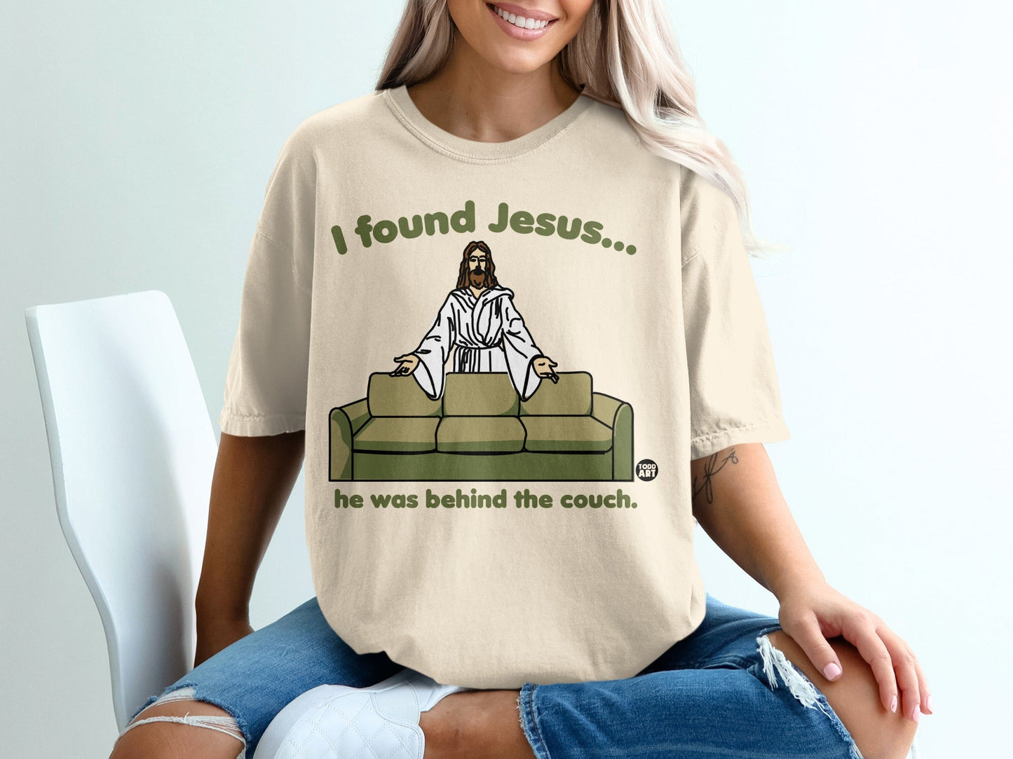 Beige t-shirt with "I found Jesus... he was behind the couch" text and Jesus graphic.