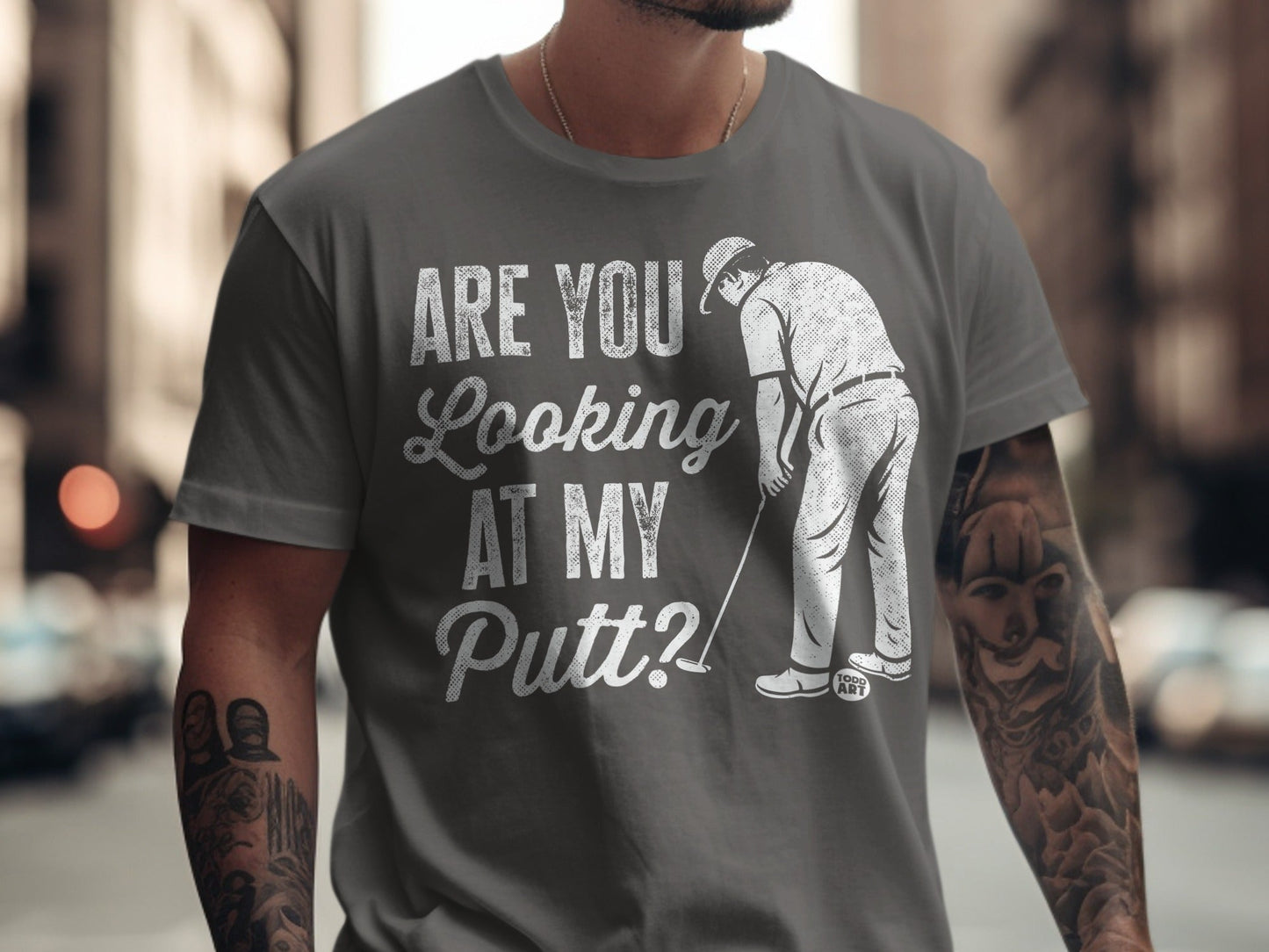 Man in grey t-shirt with "ARE YOU LOOKING AT MY PUTT?" text and golfer graphic.