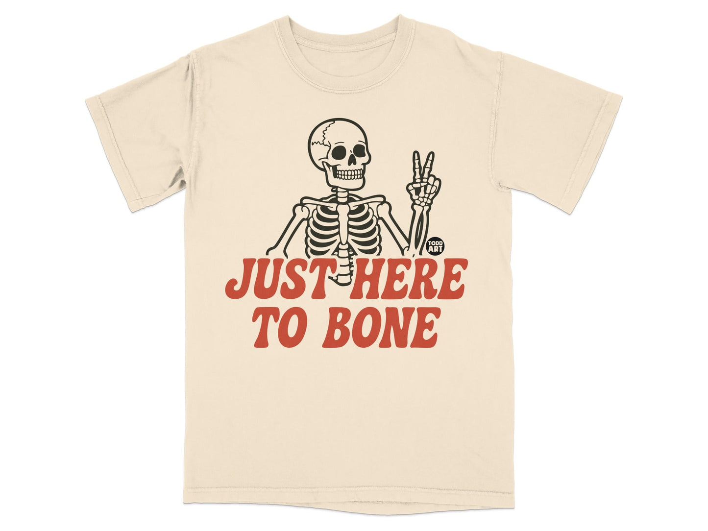Cream t-shirt with skeleton giving peace sign and text "JUST HERE TO BONE".