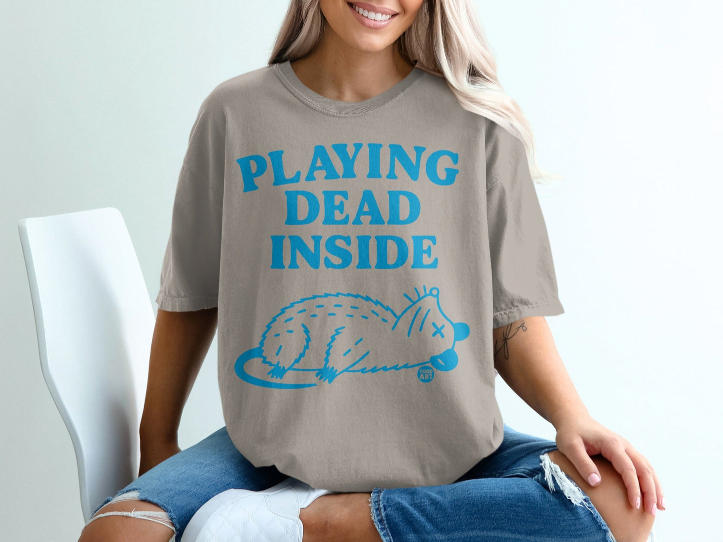 Beige t-shirt with blue text "PLAYING DEAD INSIDE" and a cartoon rat.