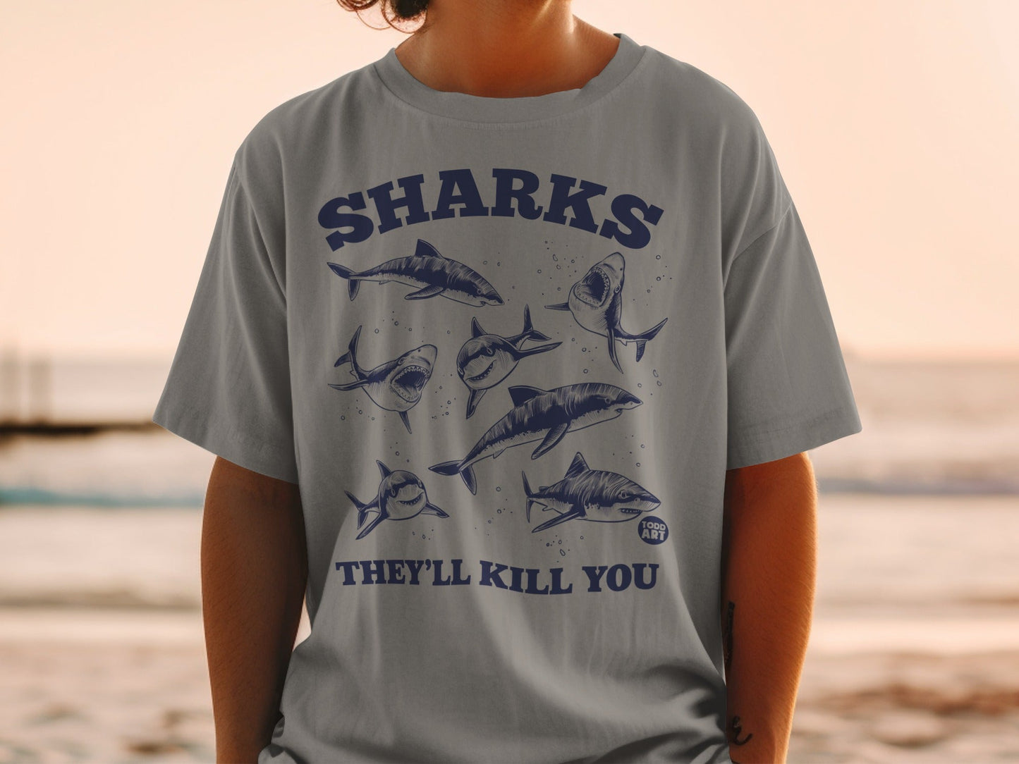 T-shirt with a dark blue graphic of several sharks and text "SHARKS THEY'LL KILL YOU".