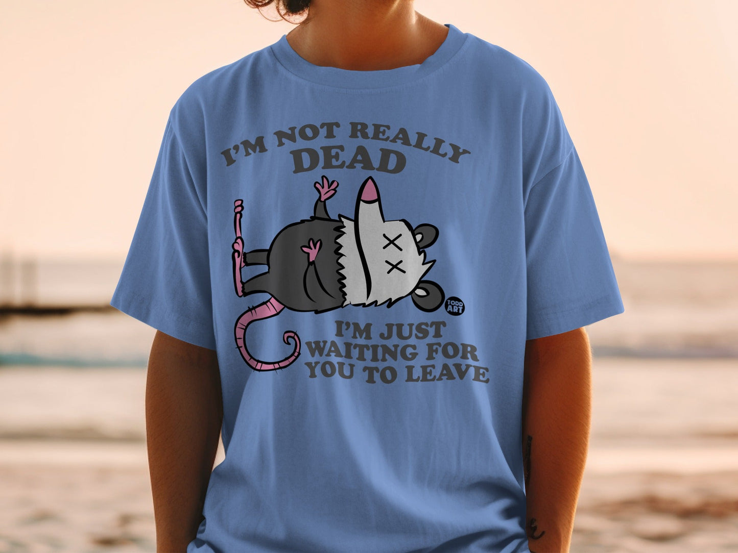 Blue t-shirt with cartoon possum playing dead and text "I'm not really dead, I'm just waiting for you to leave".