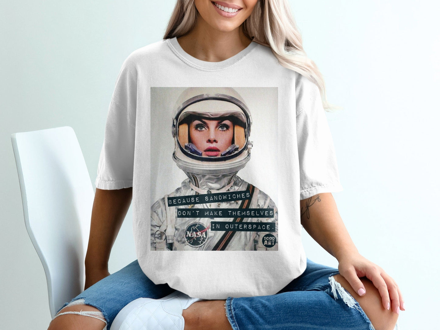 Woman wearing white t-shirt with astronaut and "Because sandwiches don't make themselves in outer space."