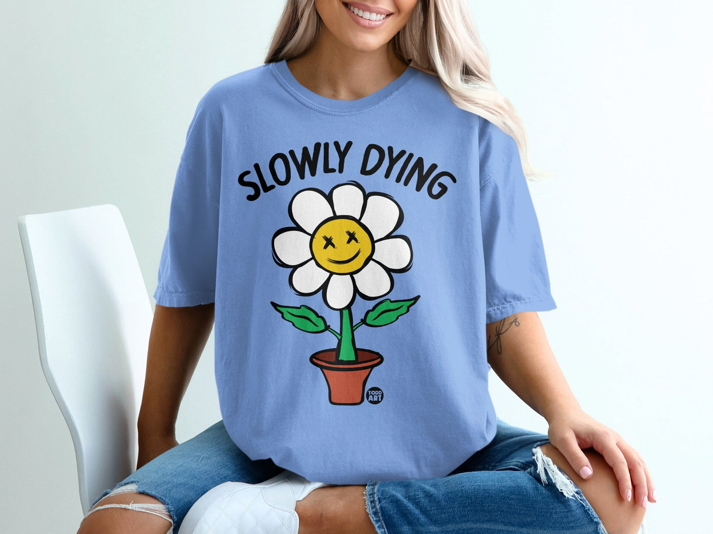 Blue t-shirt with a cartoon flower saying "Slowly Dying" on it.