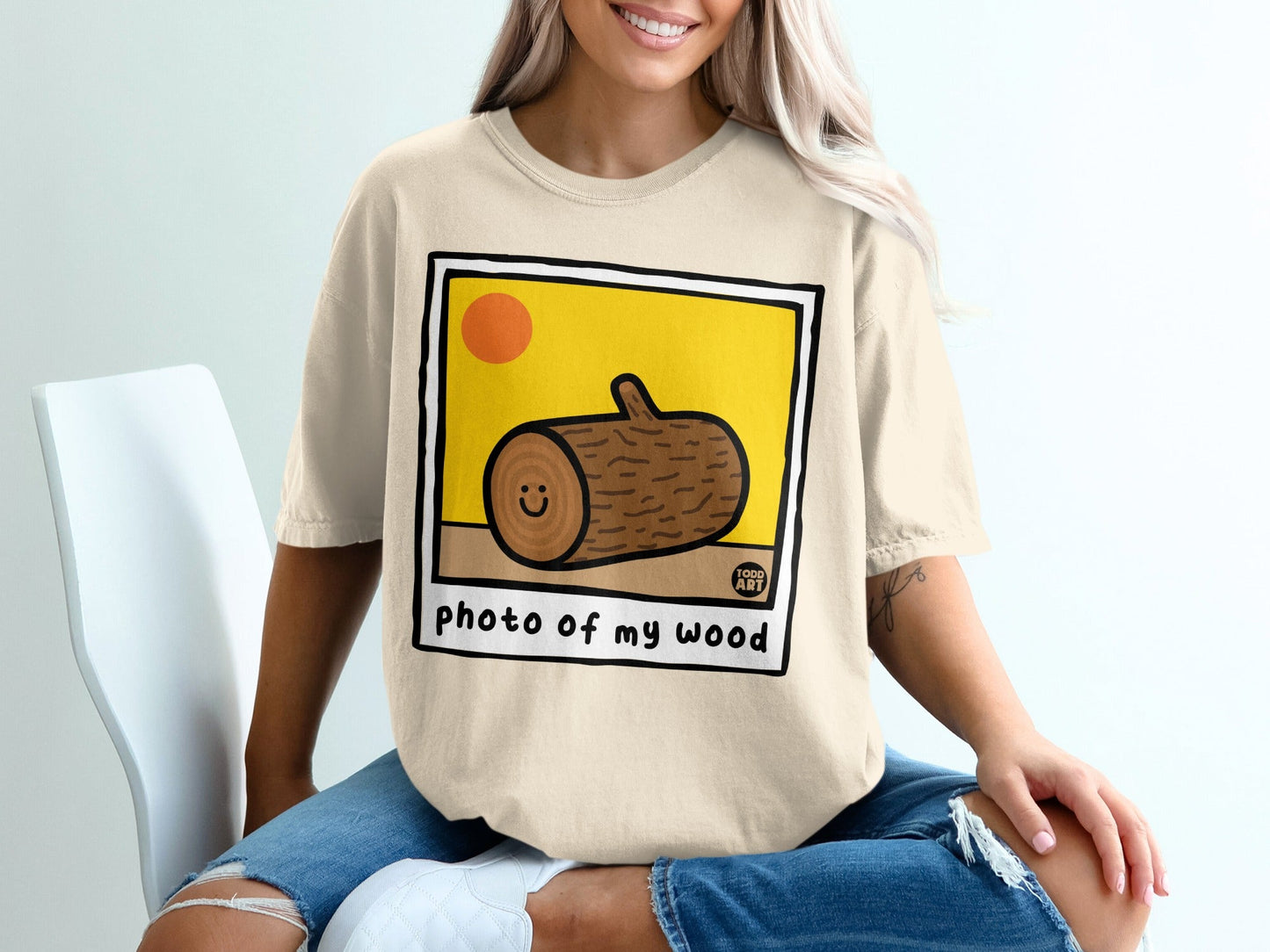 Beige t-shirt with graphic of a smiling log and text "photo of my wood".