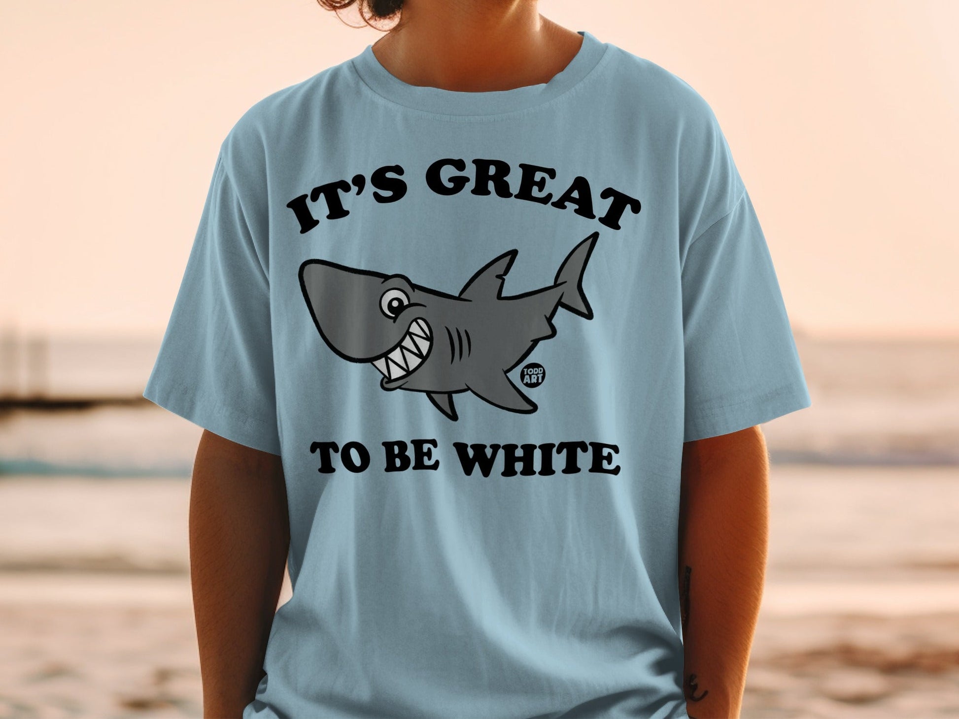 Light blue t-shirt with smiling cartoon shark and text "IT'S GREAT TO BE WHITE".