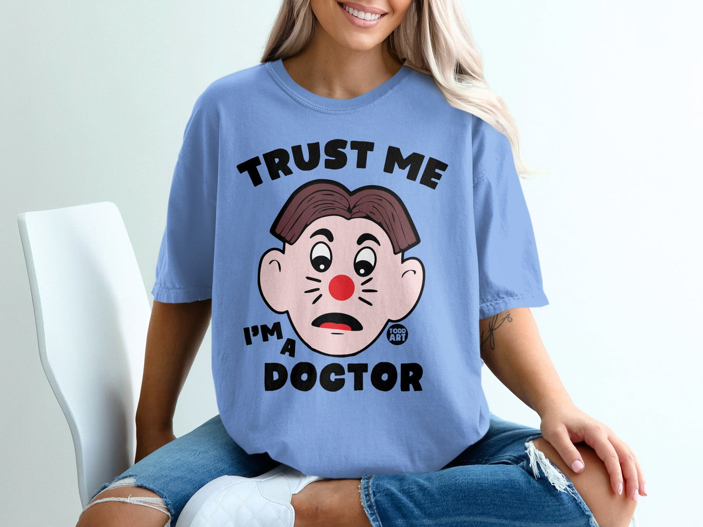 Light blue t-shirt with "Trust Me I'm A Doctor" text and clown face graphic.
