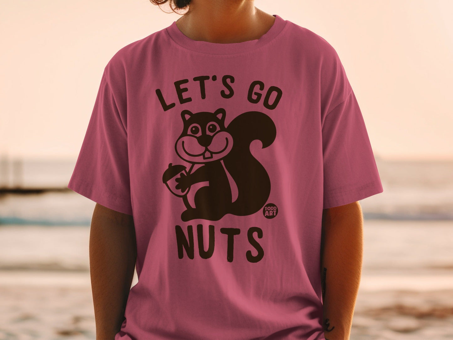 Pink t-shirt with "Let's Go Nuts" and a squirrel holding an acorn.