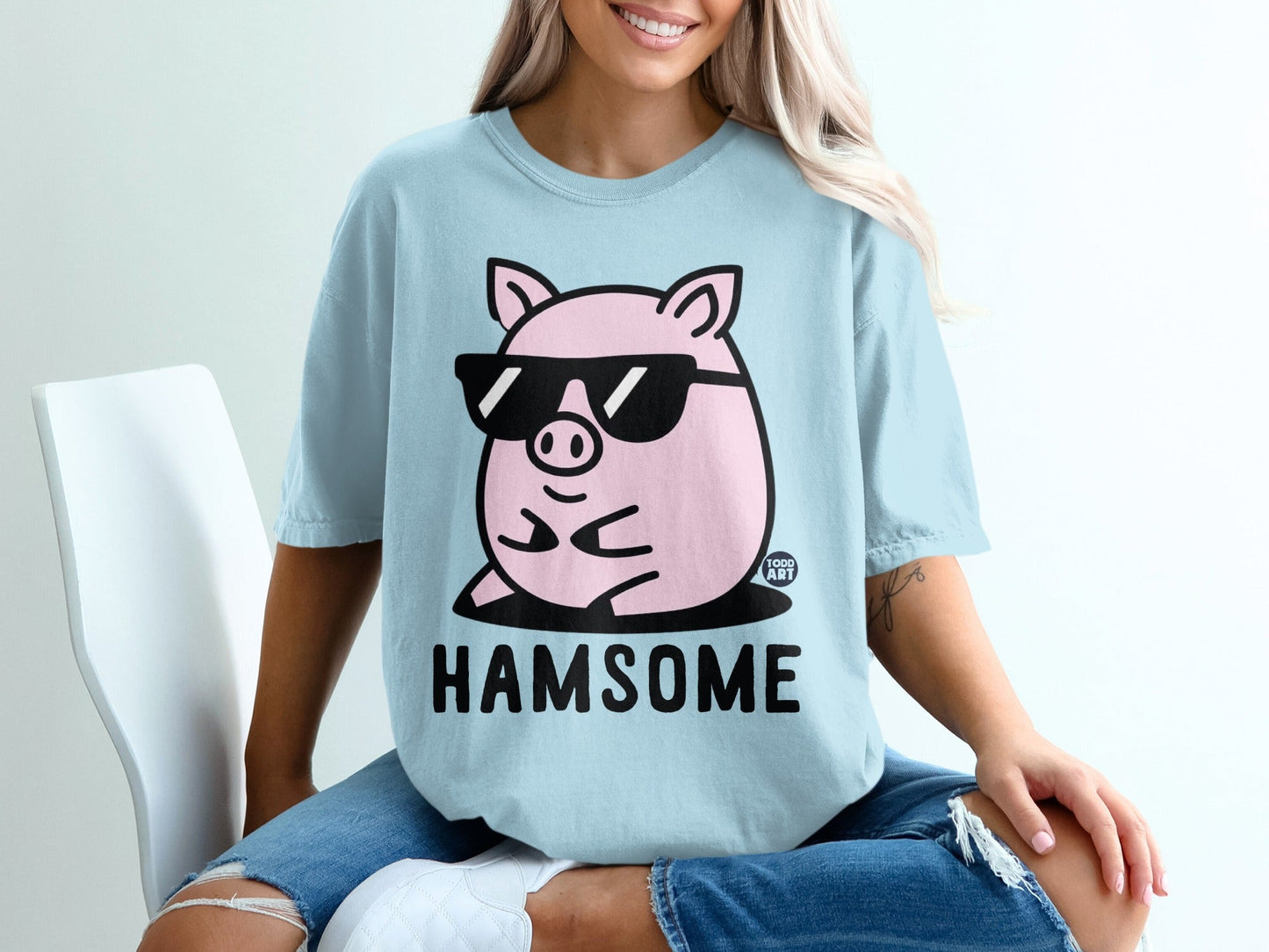 Light blue t-shirt with a cartoon pig wearing sunglasses and the word "HAMsome".
