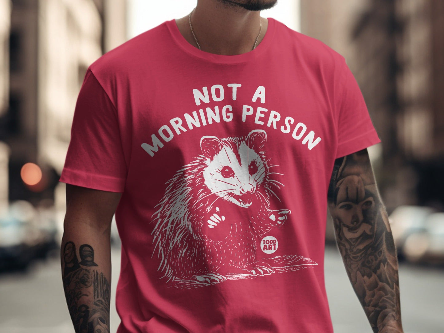 Red t-shirt with white graphic of a possum and text "NOT A MORNING PERSON".