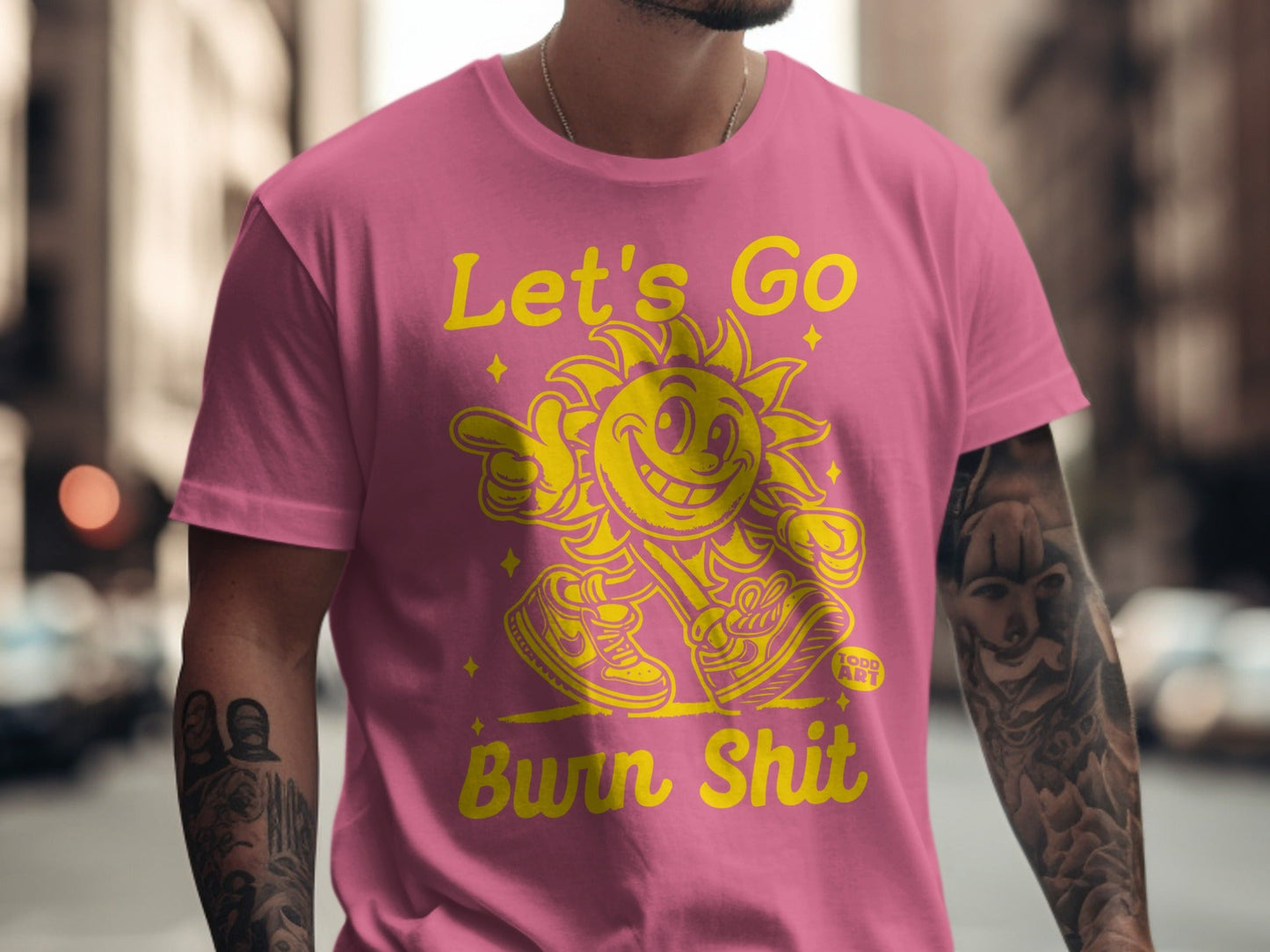 Pink t-shirt with yellow cartoon sun graphic and text "Let's Go Bwn Shit".