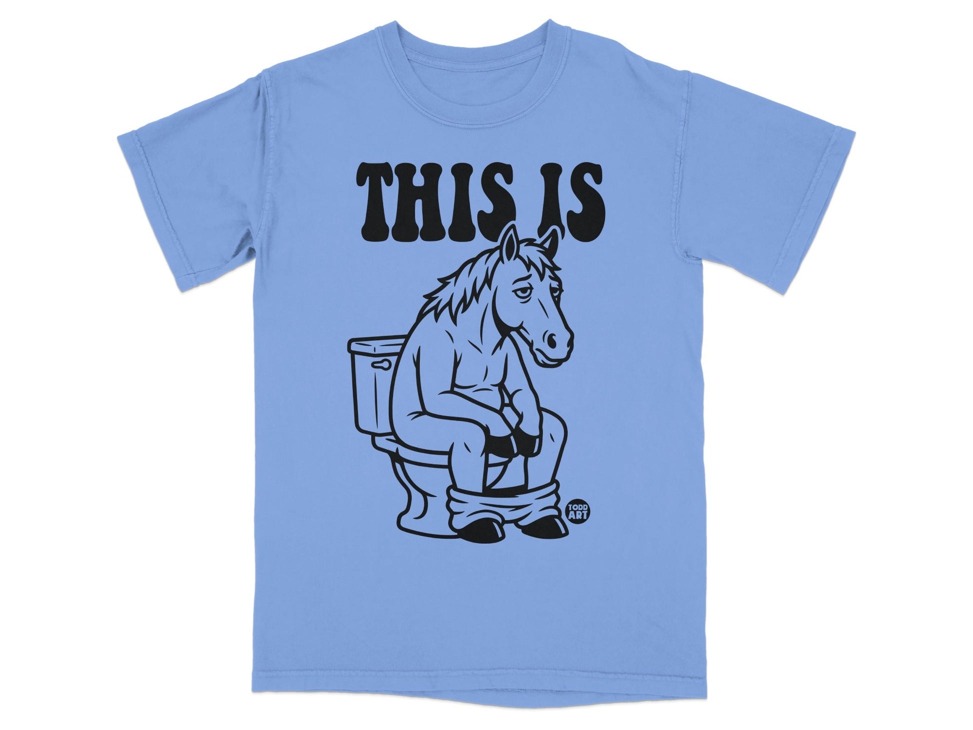 Light blue t-shirt with black text "THIS IS" and illustration of a horse on a toilet.
