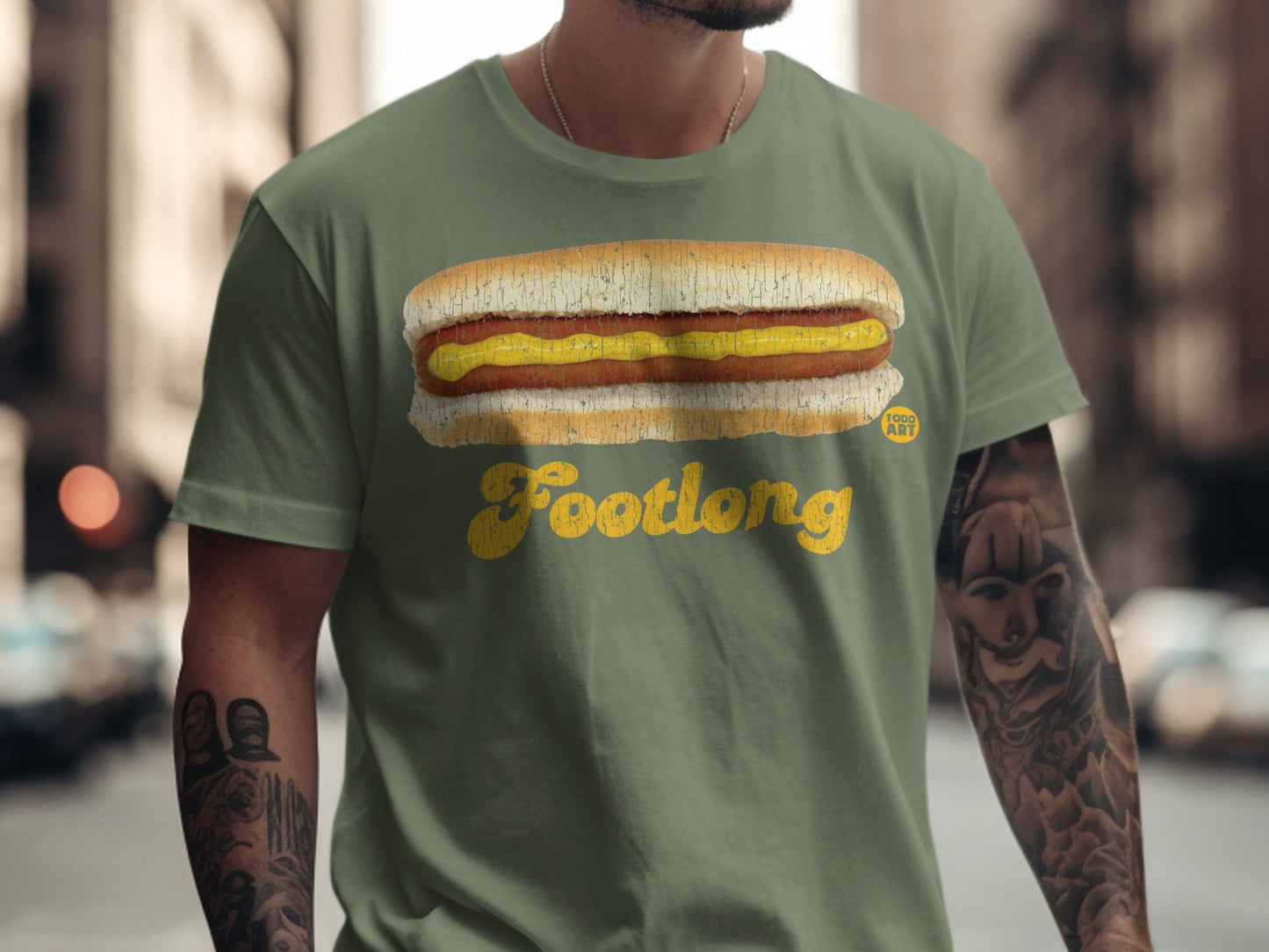 Green t-shirt with a yellow footlong hot dog and mustard graphic.