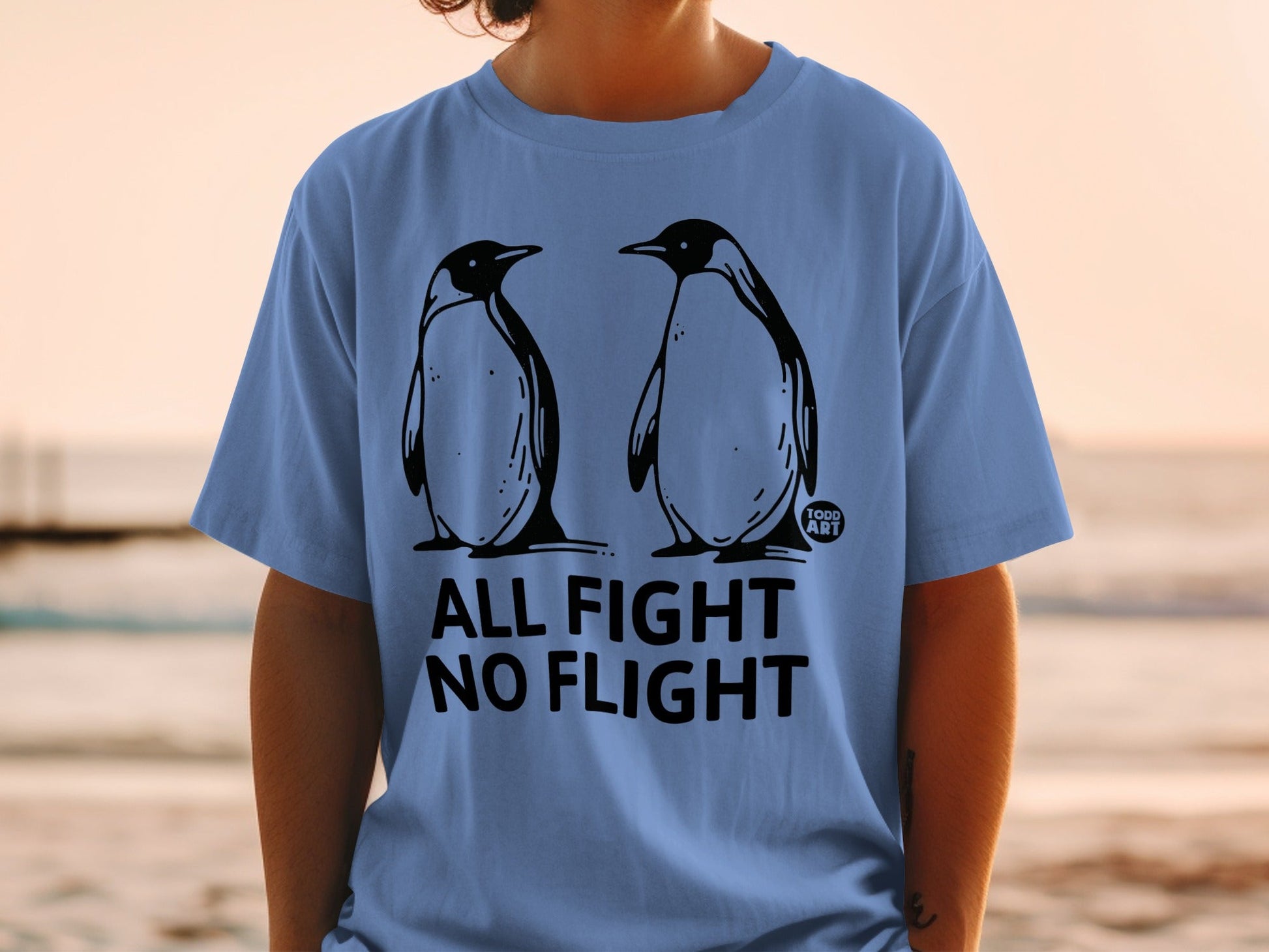 Two penguins stand facing each other on a t-shirt with the text "ALL FIGHT NO FLIGHT".