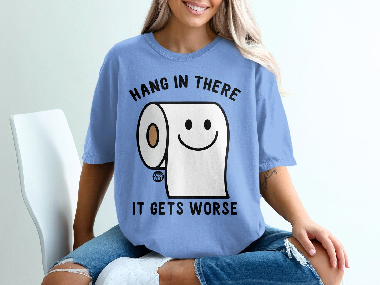 Blue t-shirt with humorous toilet paper character saying "Hang in there, it gets worse."