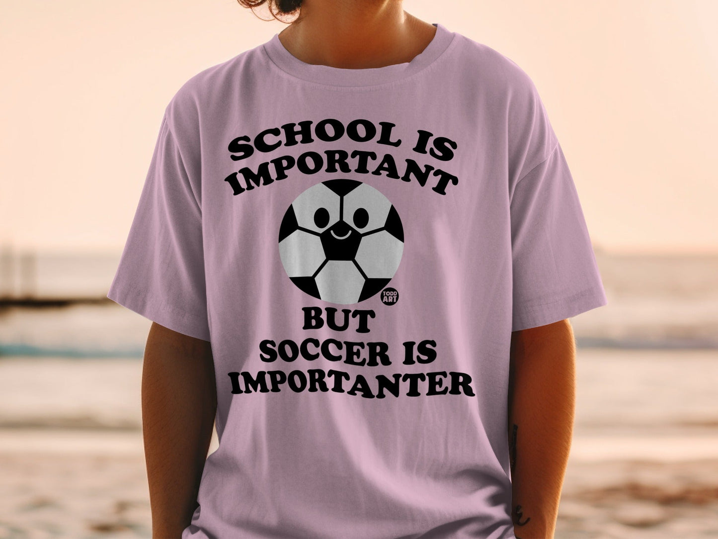 Pink t-shirt with "School is Important, But Soccer is Importanter" text and soccer ball graphic.