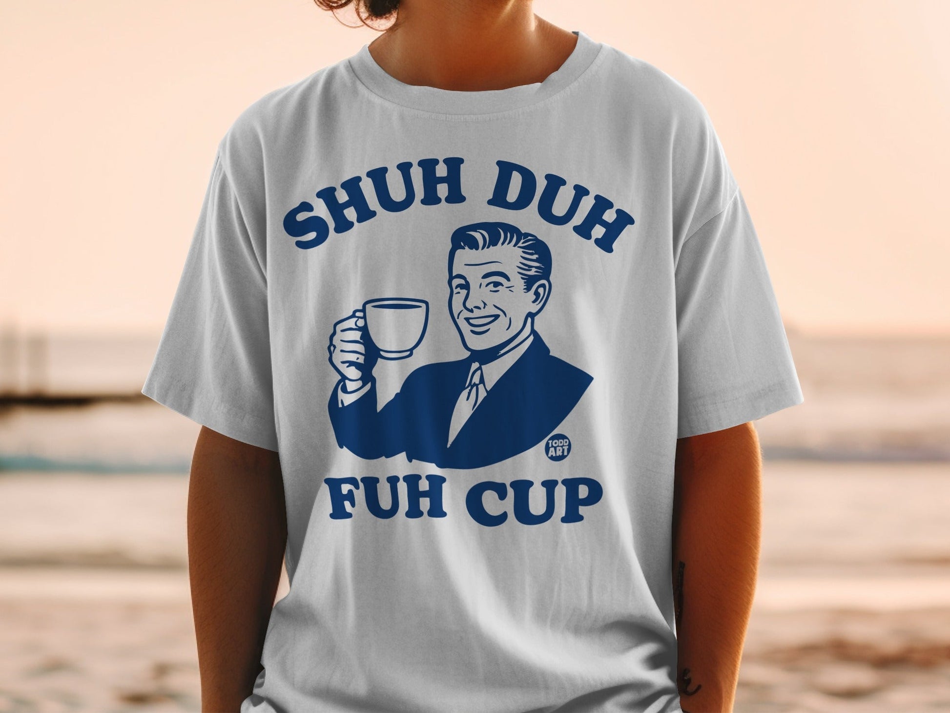 White t-shirt with blue graphic of man holding "Shuh Duh Fuh Cup".