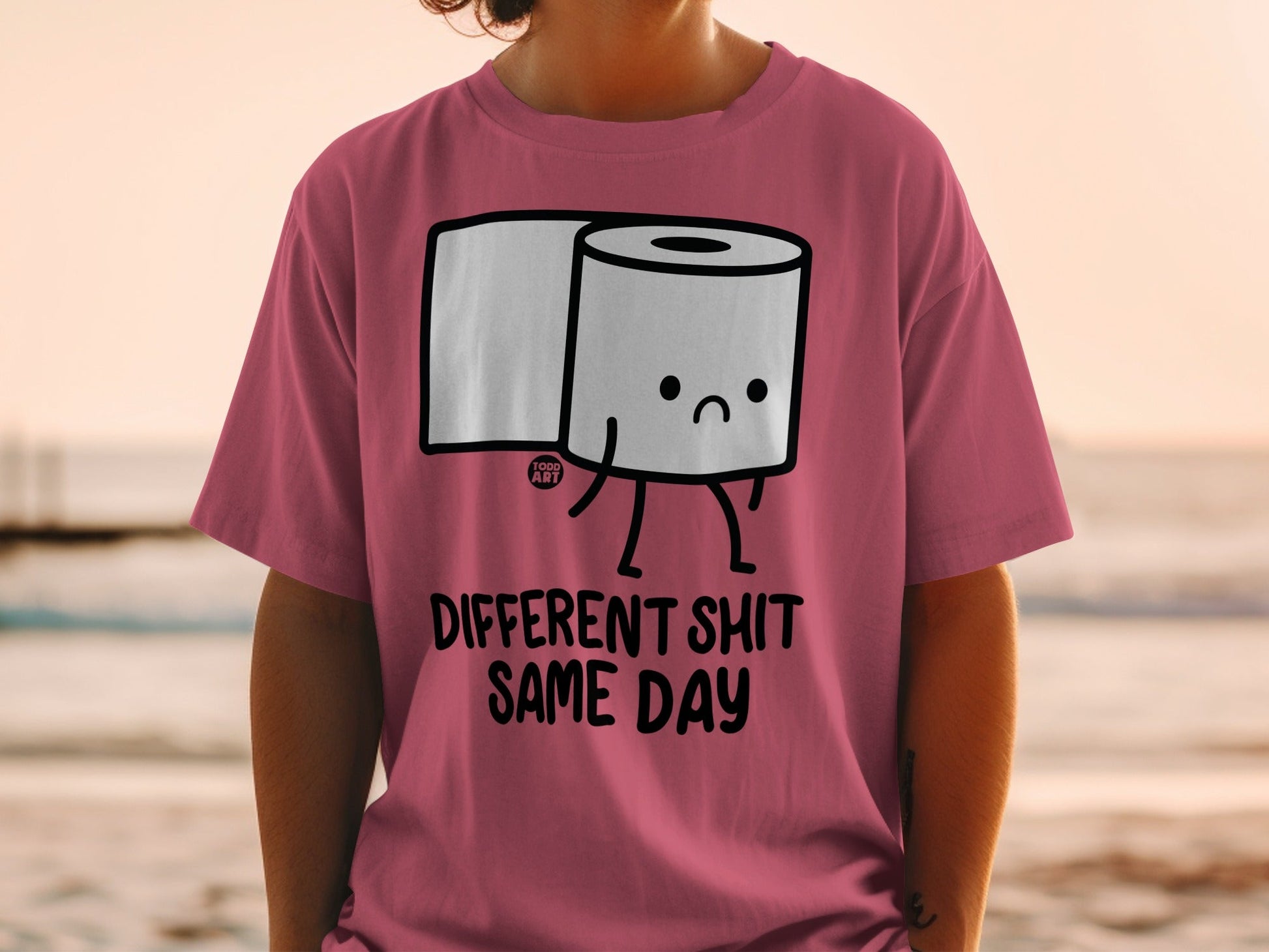 Pink t-shirt with cartoon toilet paper saying "Different Shit Same Day".