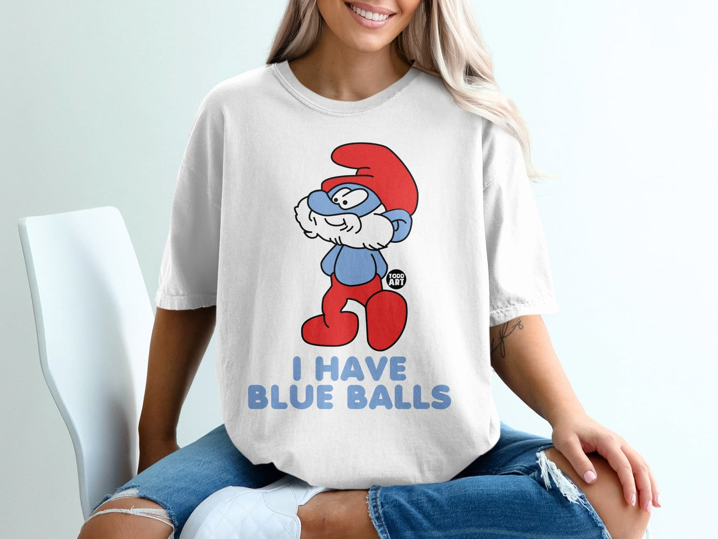 Smurf character with red hat and pants on white t-shirt, "I HAVE BLUE BALLS" text.