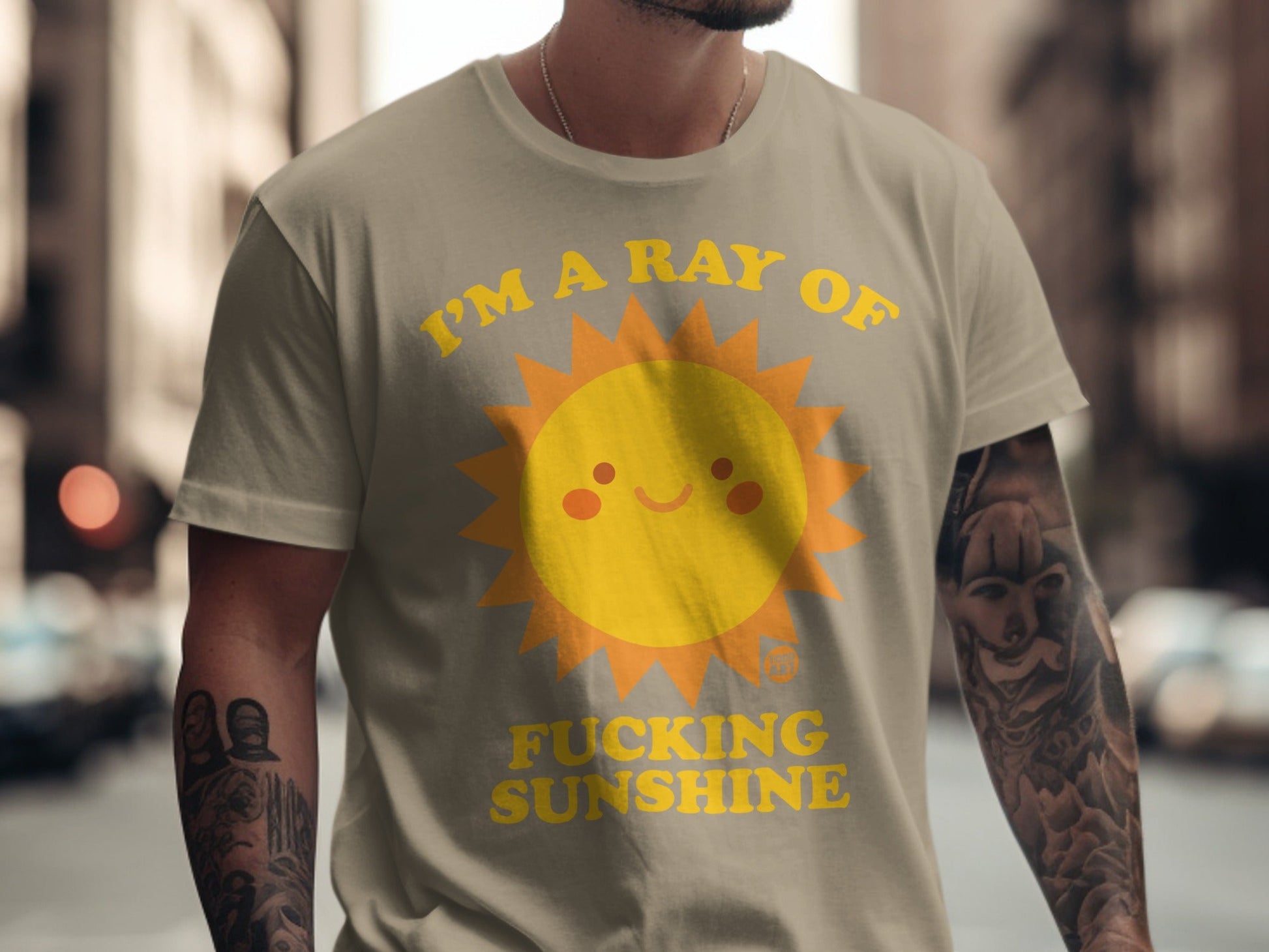 Tan t-shirt with smiling sun graphic and "I'M A RAY OF FUCKING SUNSHINE" text.