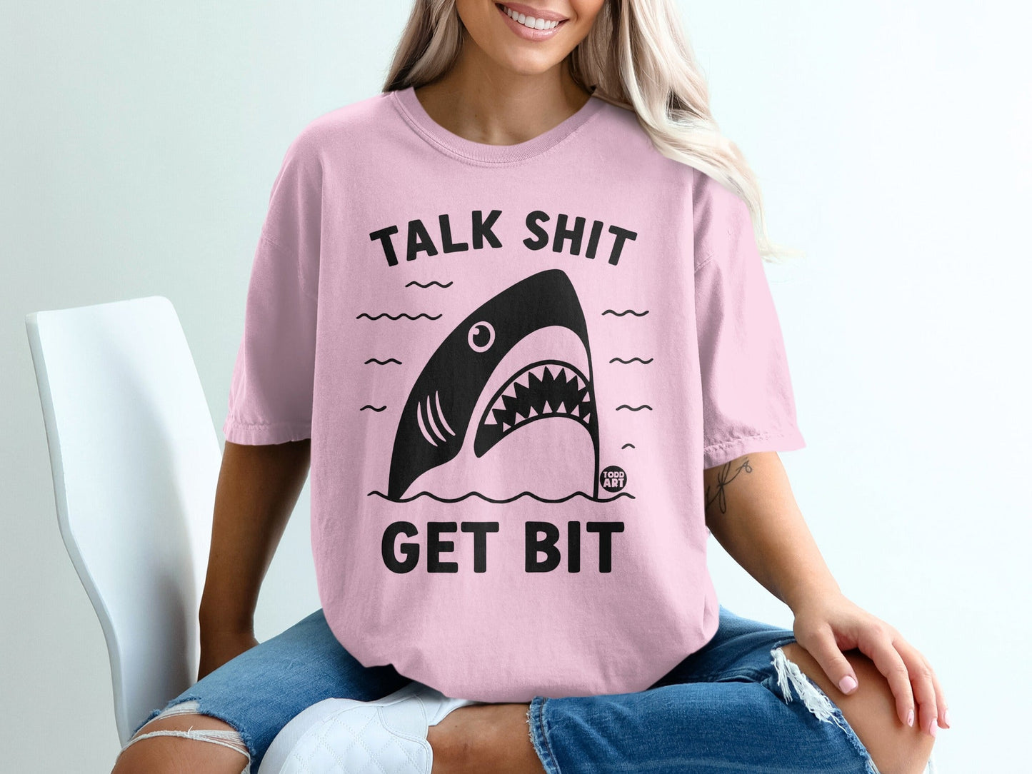 Pink t-shirt with shark graphic and "TALK SHIT GET BIT" text.