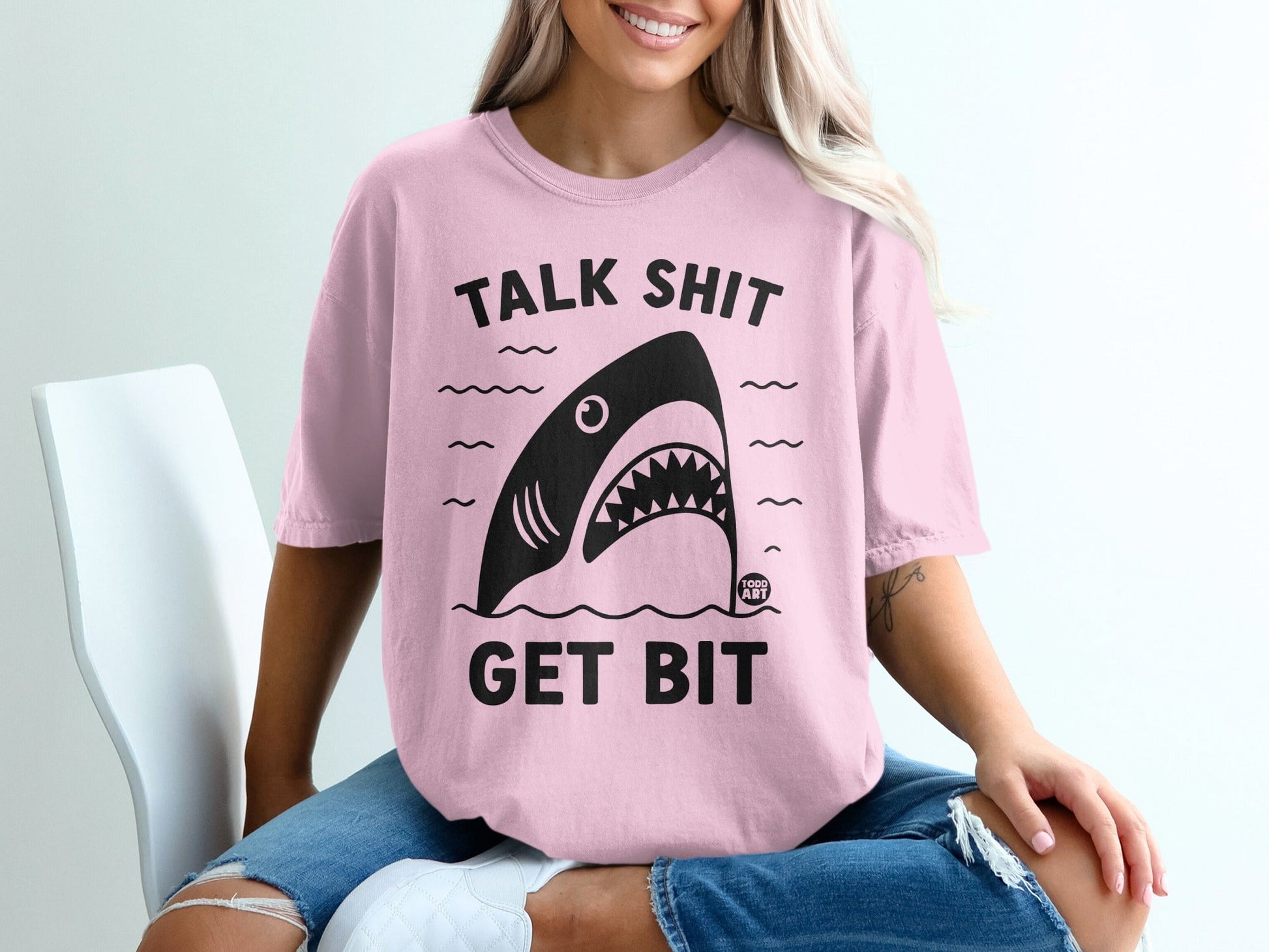Pink t-shirt with shark graphic and "TALK SHIT GET BIT" text.