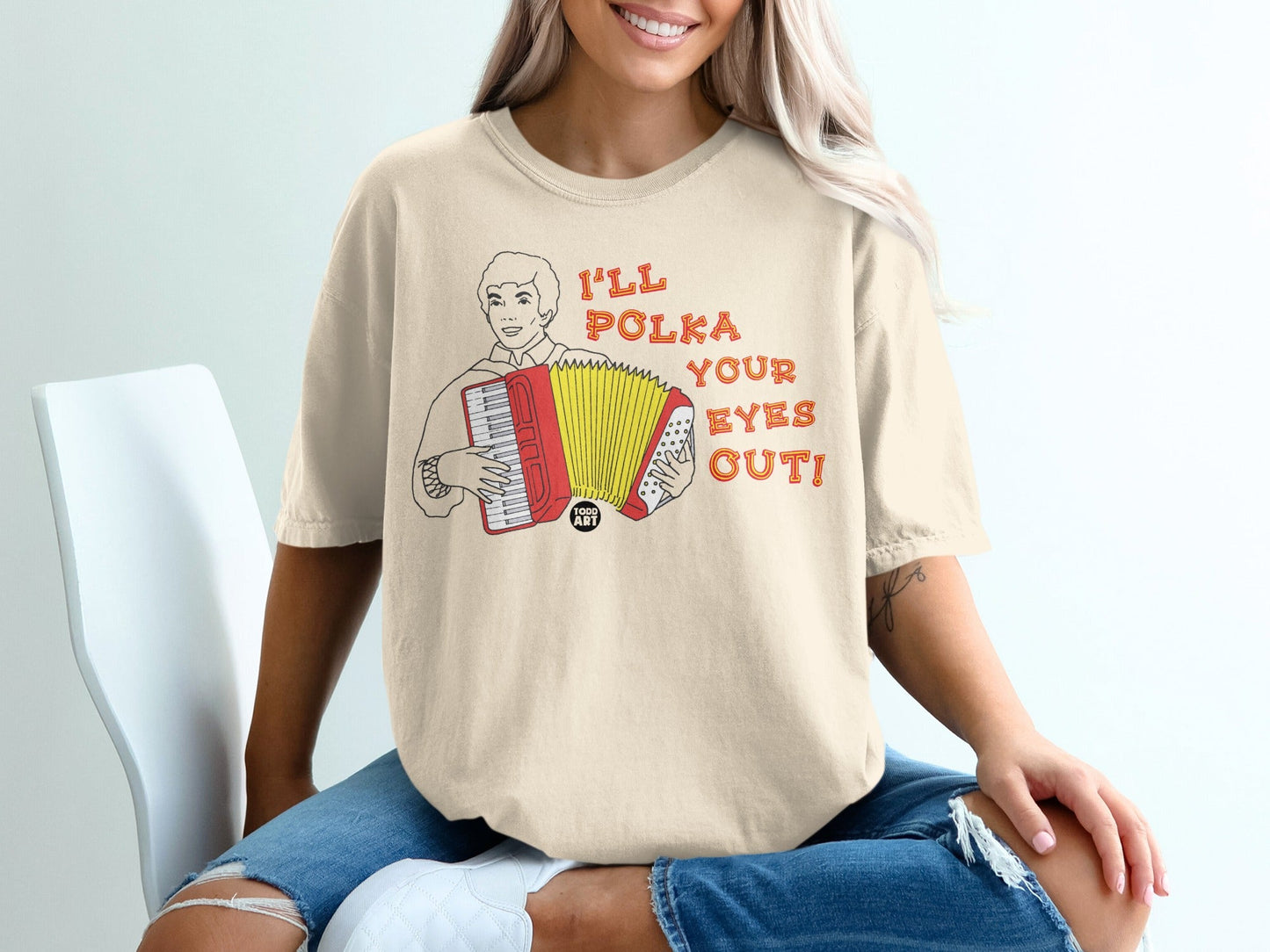 T-shirt with graphic of a smiling accordion player and text "I'll Polka Your Eyes Out".