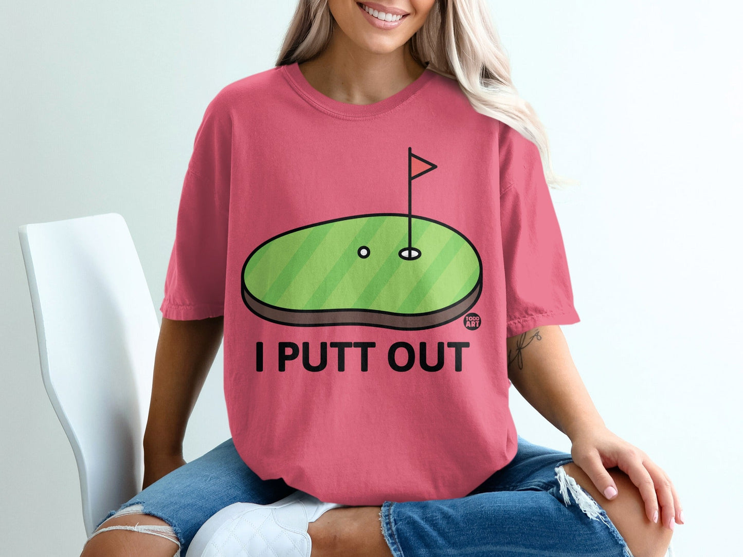 Pink t-shirt with "I PUTT OUT" and a cartoon golf hole graphic.