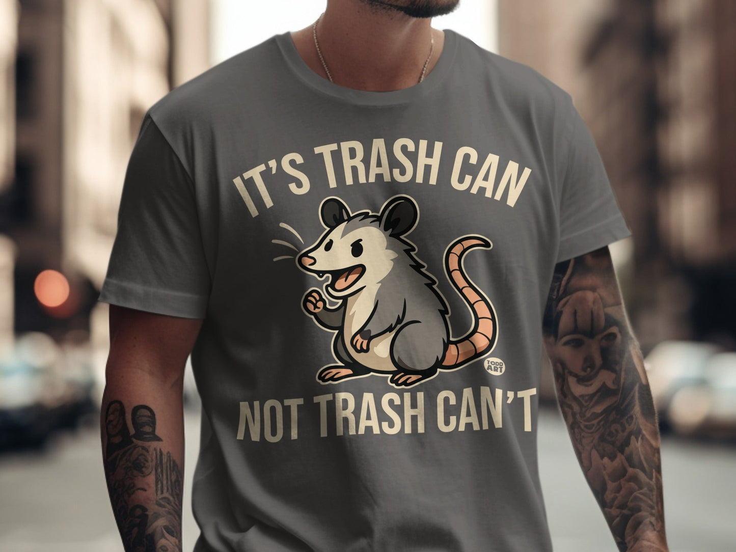 Grey t-shirt with opossum graphic and text "It's trash can, not trash can't".