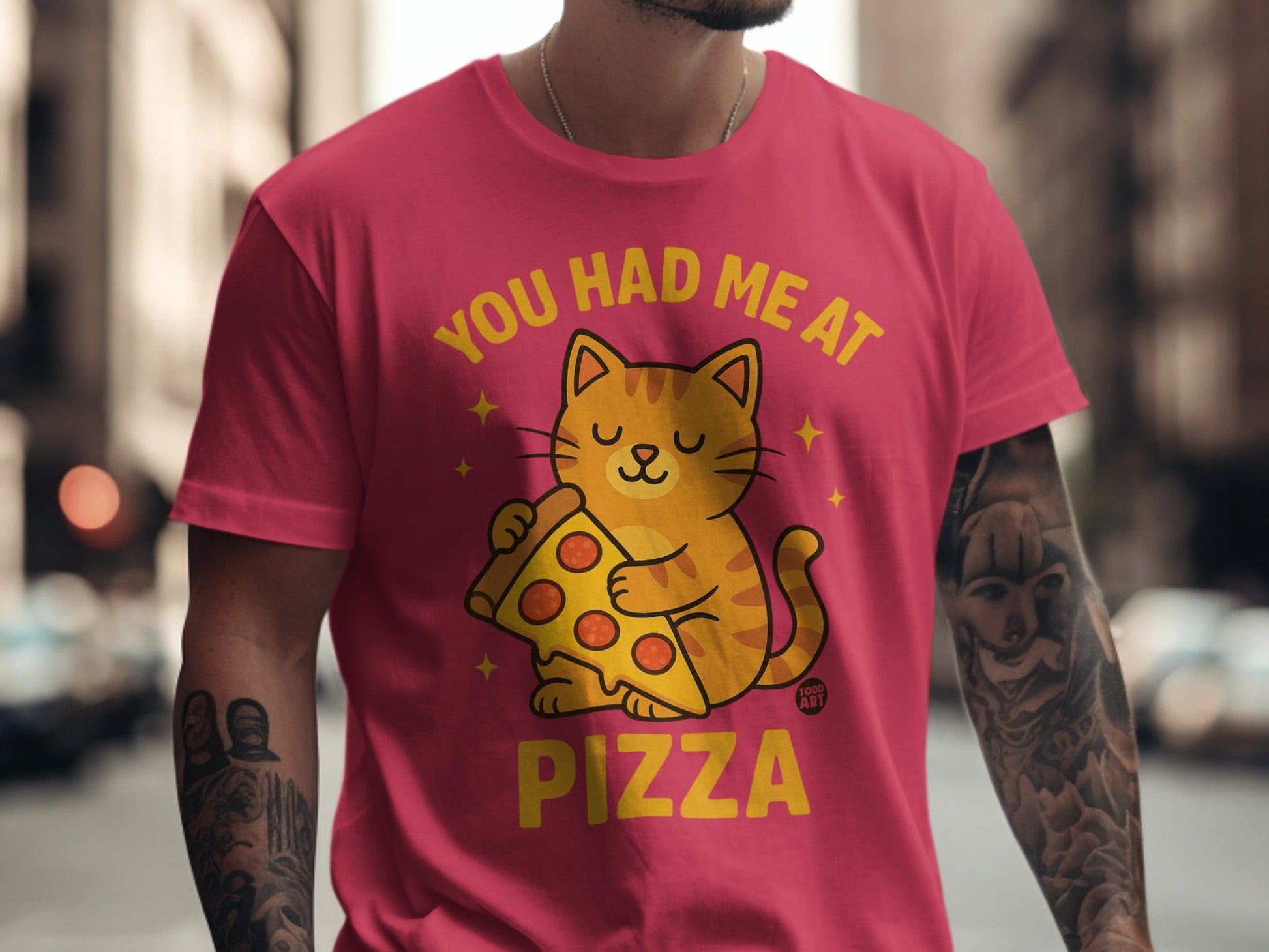 Orange cat holding pizza slice on pink t-shirt with text "YOU HAD ME AT PIZZA".