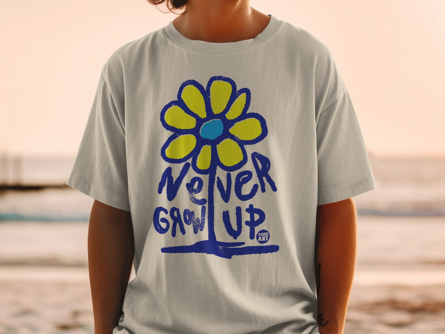 Gray t-shirt with blue and yellow flower graphic and text "Never Grow Up".