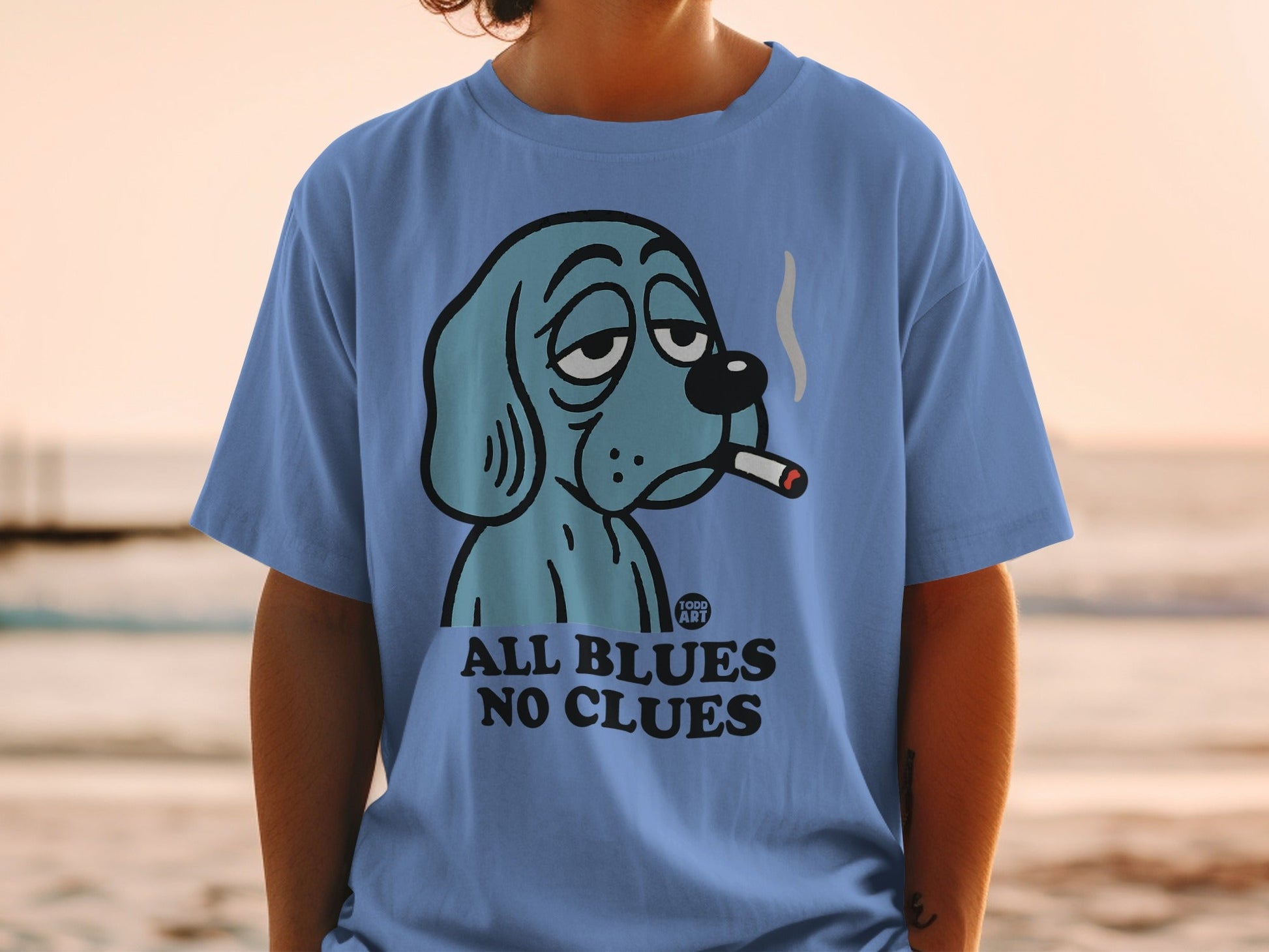Blue dog wearing a hat and smoking a cigarette on a t-shirt.