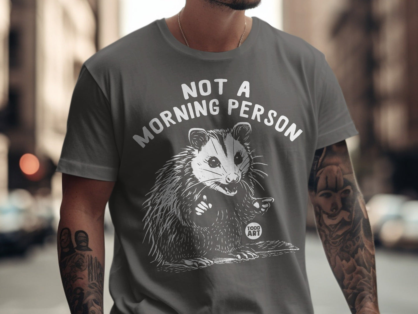 Gray t-shirt with white text "NOT A MORNING PERSON" and a startled opossum graphic.