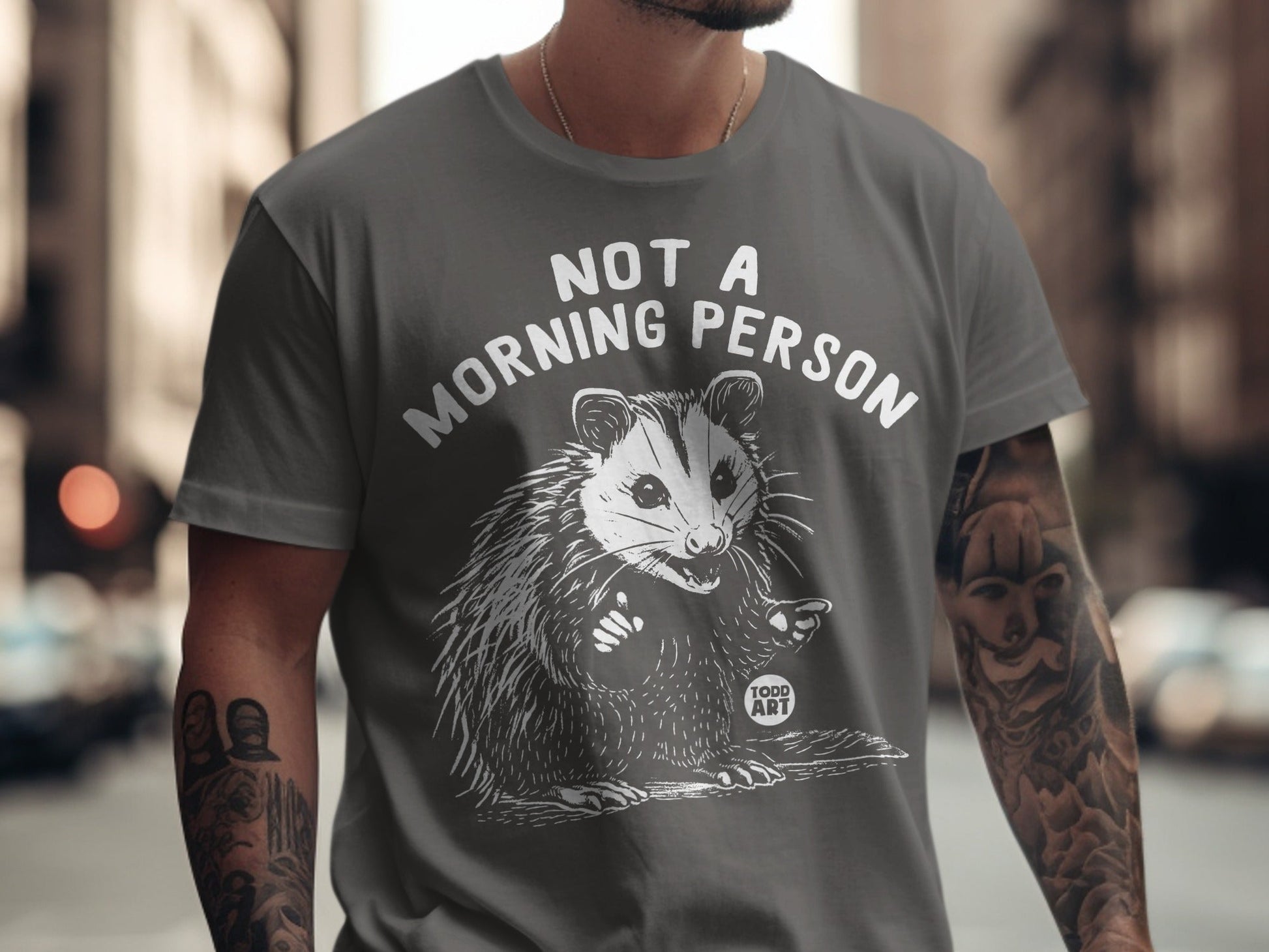 Gray t-shirt with white text "NOT A MORNING PERSON" and a startled opossum graphic.