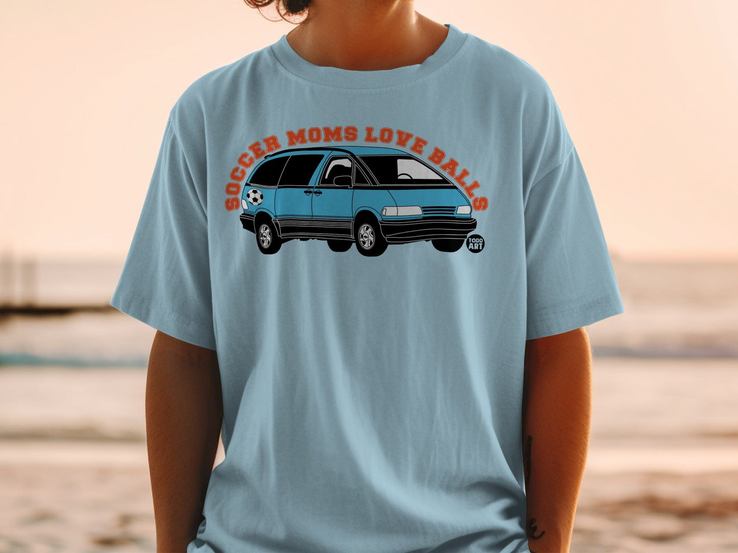 Light blue t-shirt with a blue minivan and soccer ball graphic and text.