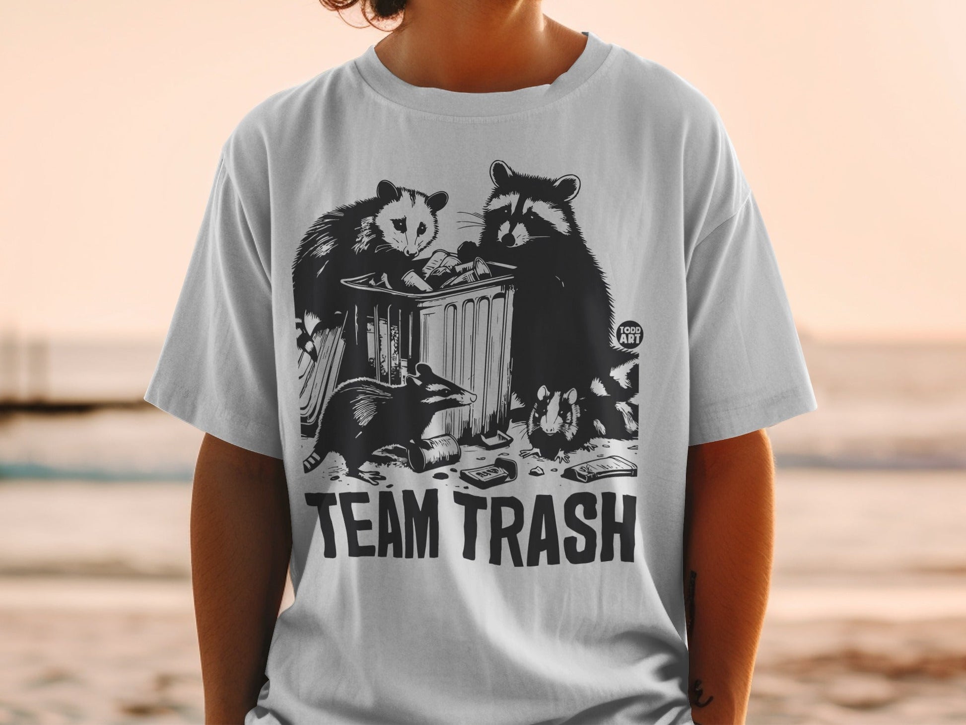T-shirt with "TEAM TRASH" text and raccoons and opossum in a trash can.