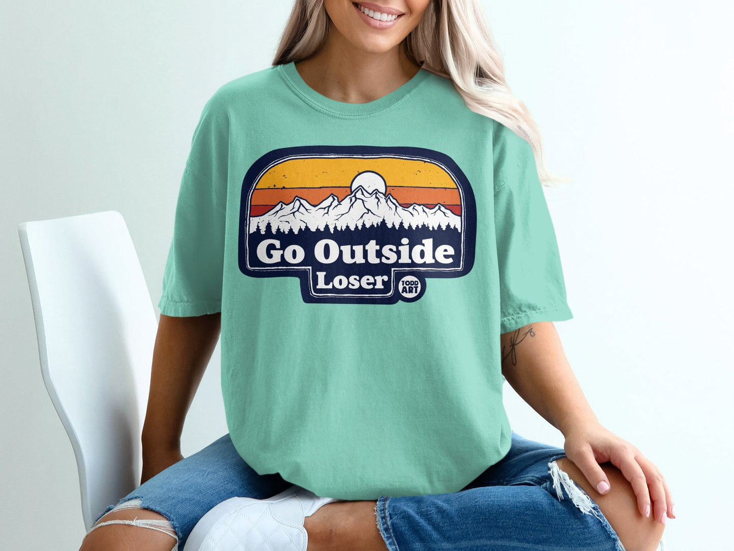 Mint green t-shirt with "Go Outside Loser" text and mountain sunset graphic.