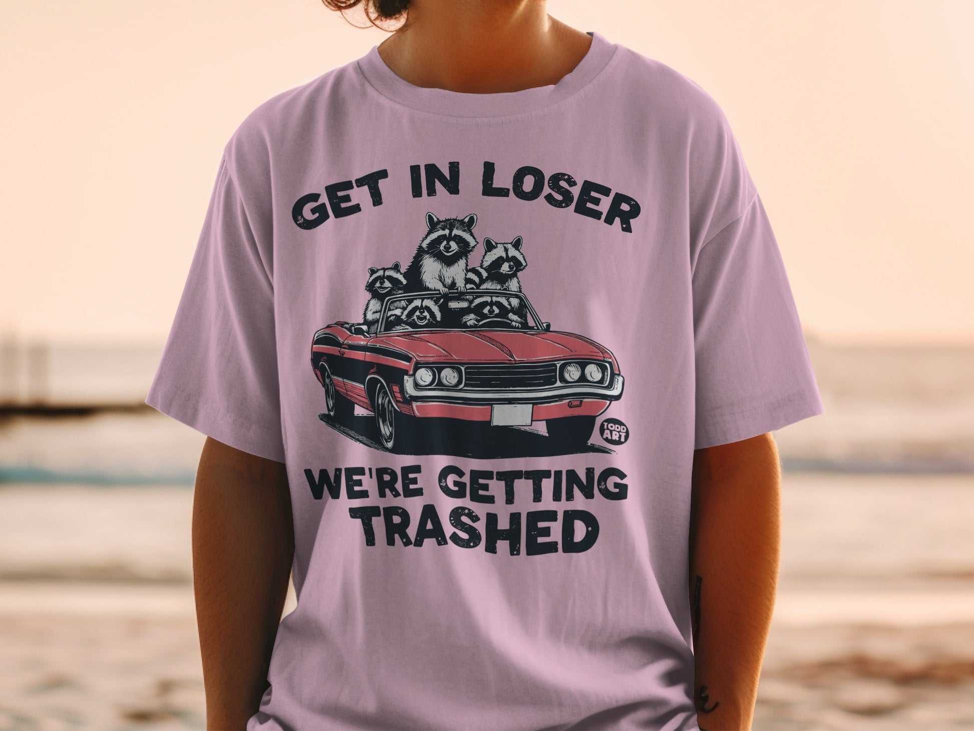 T-shirt with raccoons in a convertible, text "GET IN LOSER WE'RE GETTING TRASHED".