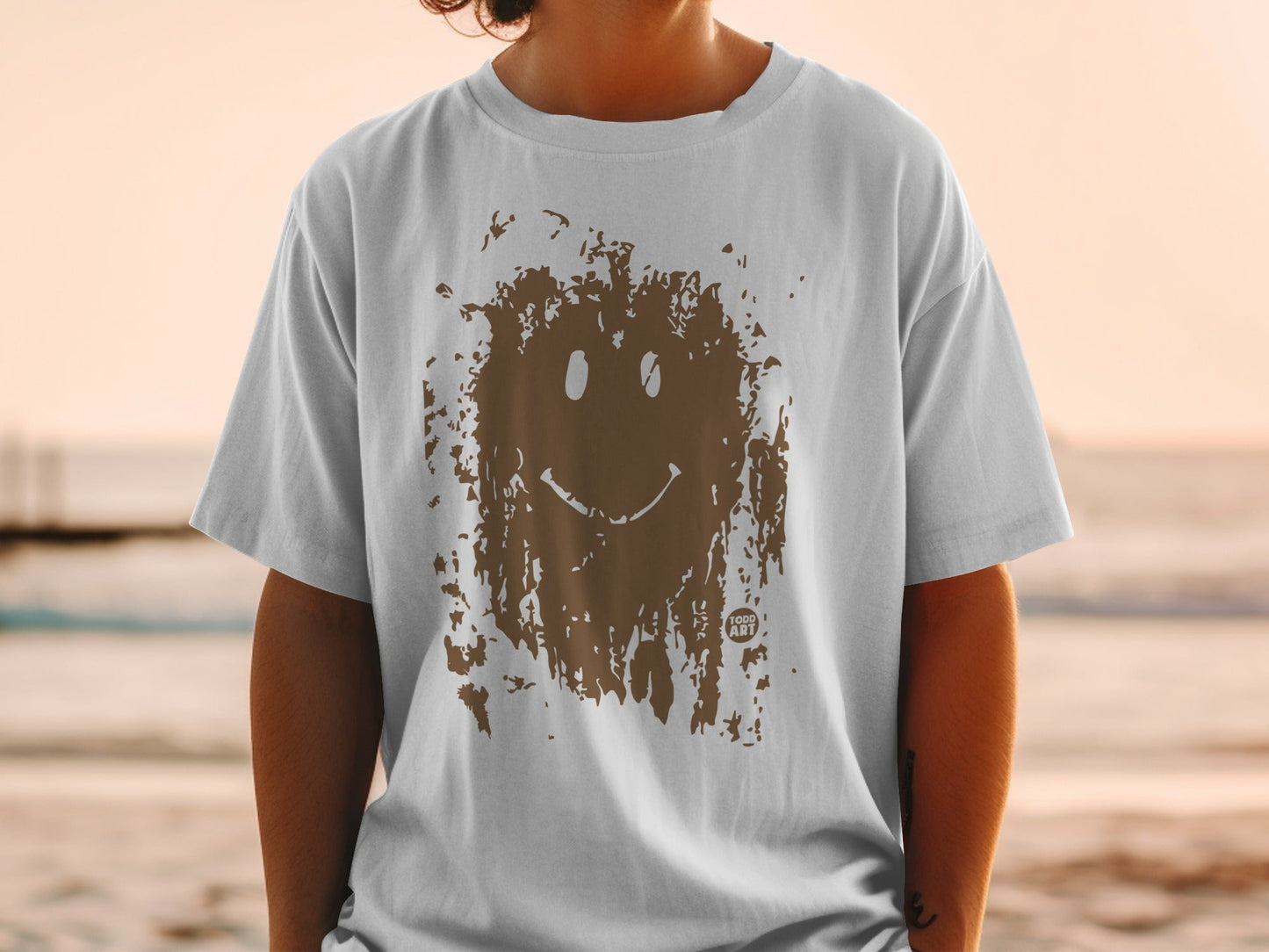 White t-shirt with brown mud-splattered smiley face graphic and "FUN ART" text.