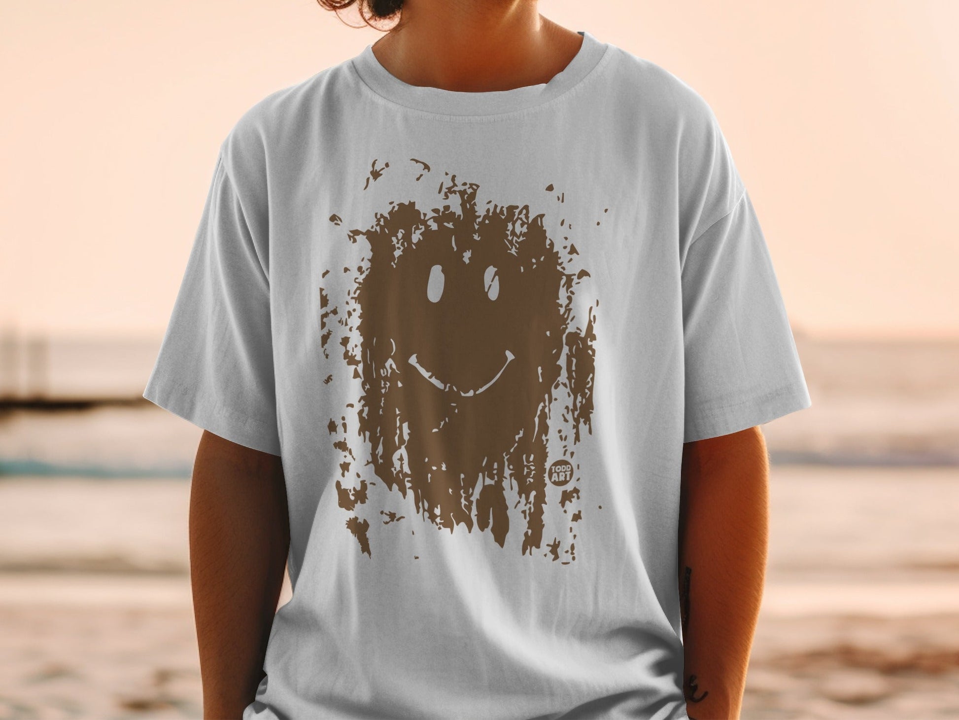 White t-shirt with brown mud-splattered smiley face graphic and "FUN ART" text.