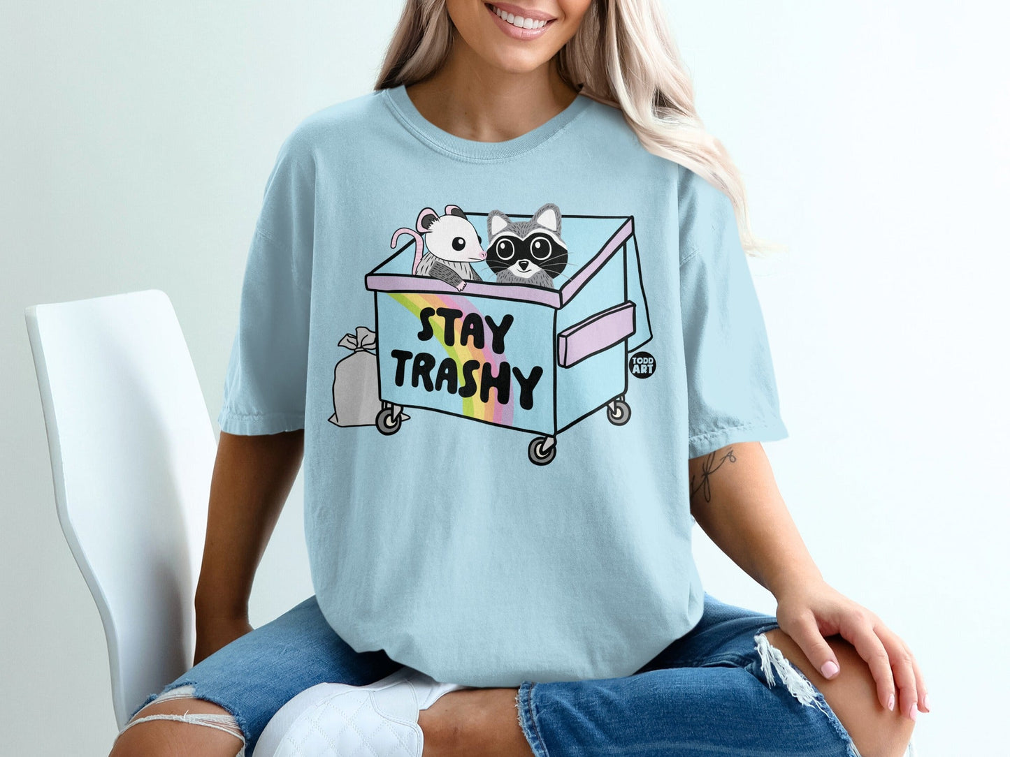 Light blue t-shirt with a raccoon and mouse in a trash can.