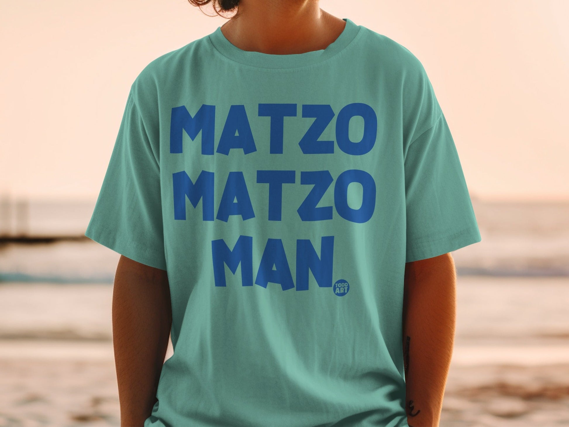 Teal t-shirt with "MATZO MATZO MAN" and "YOGG ART" logo.