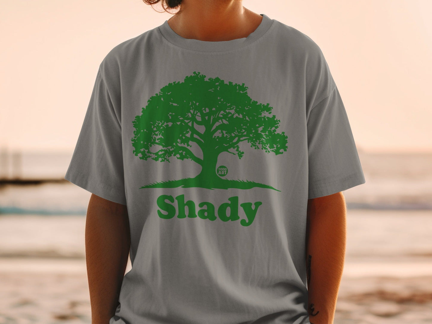Green tree logo with "Shady" text on a grey t-shirt.