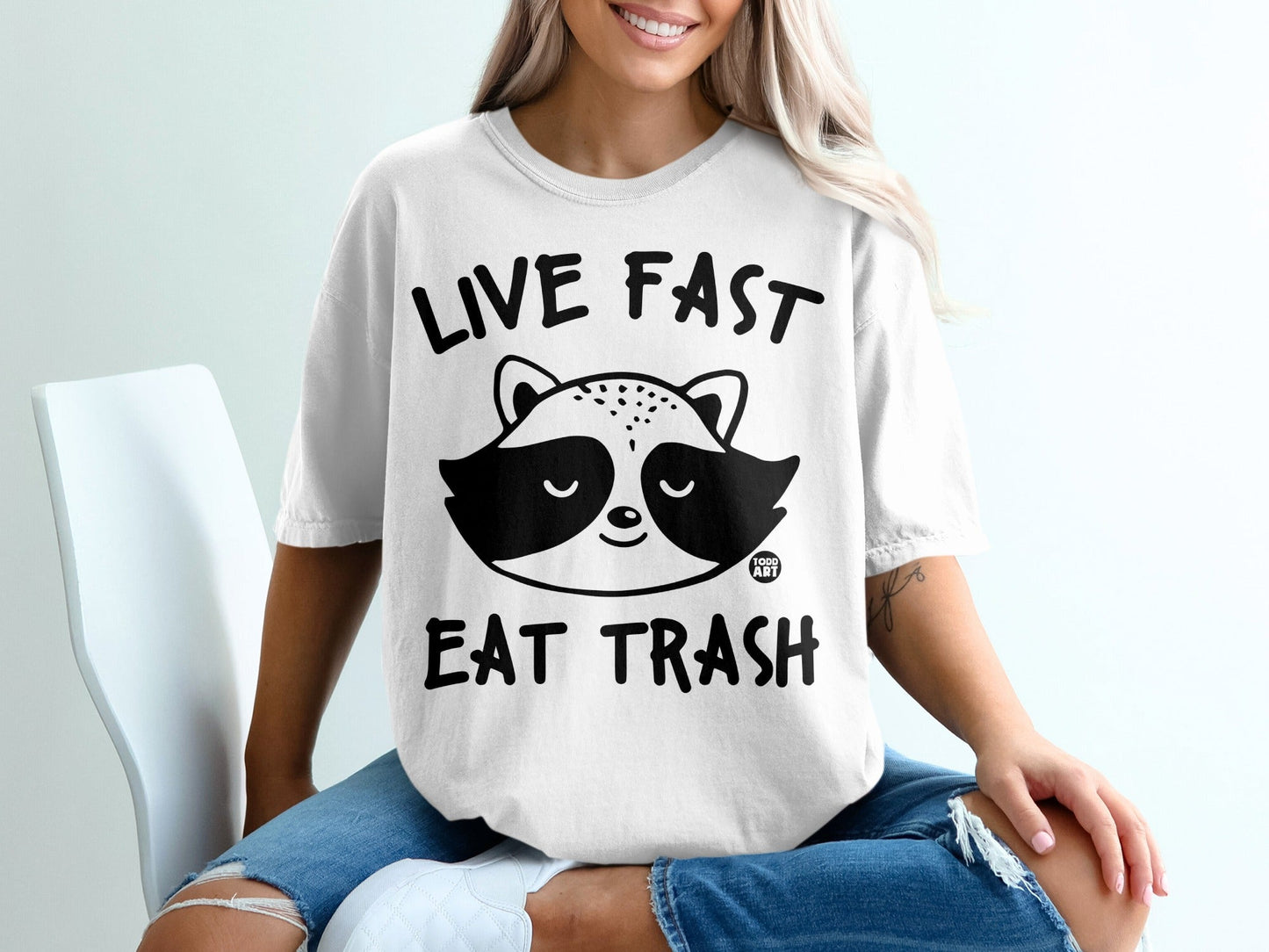 White t-shirt with "LIVE FAST EAT TRASH" and raccoon graphic.