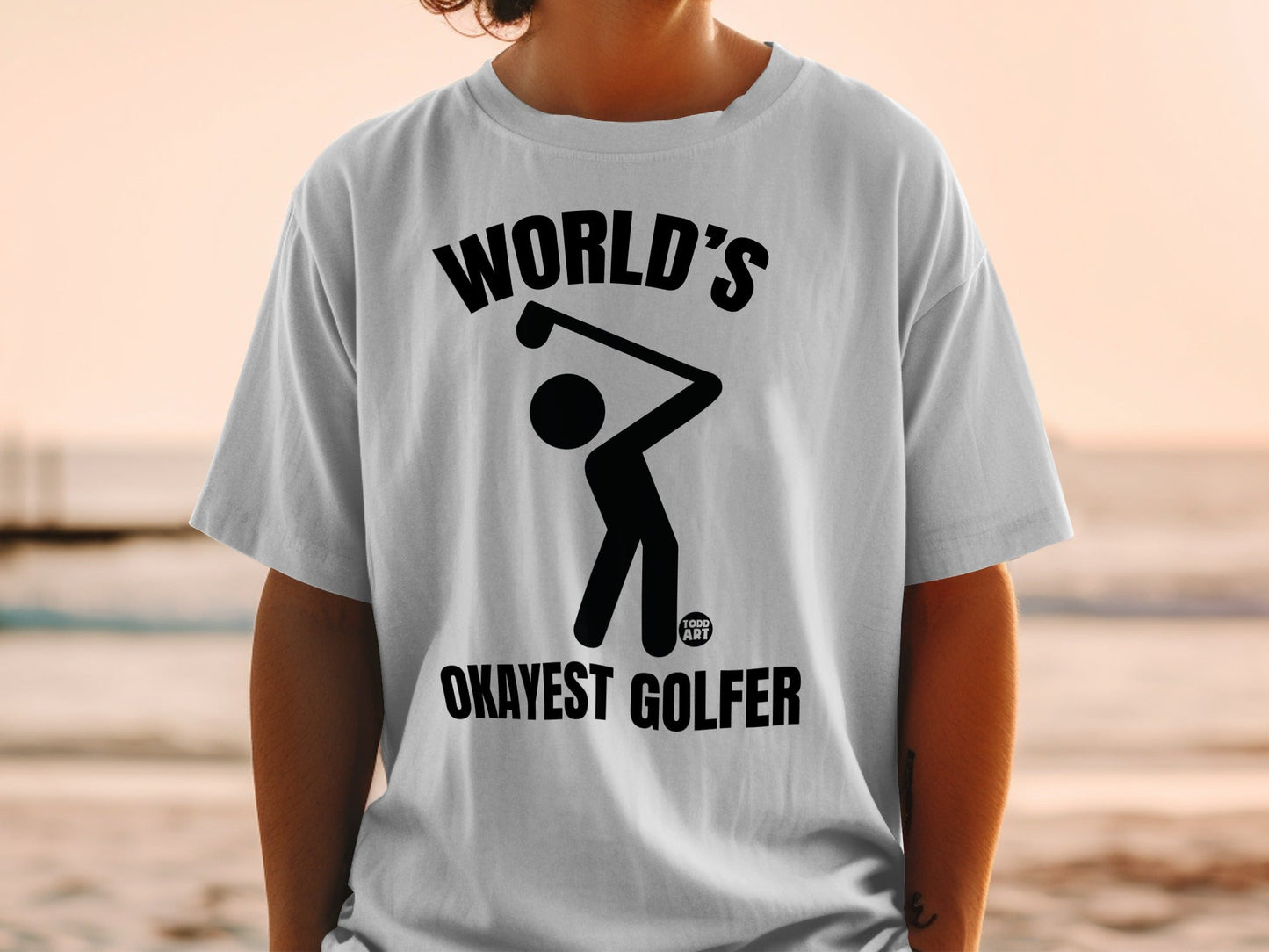 T-shirt with a black graphic of a golfer and the text "WORLD'S OKAYEST GOLFER".