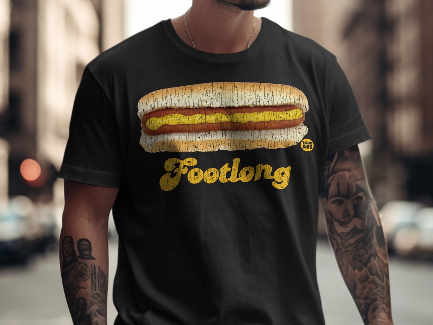 Black t-shirt with a cartoon footlong hot dog graphic and "Footlong" text.
