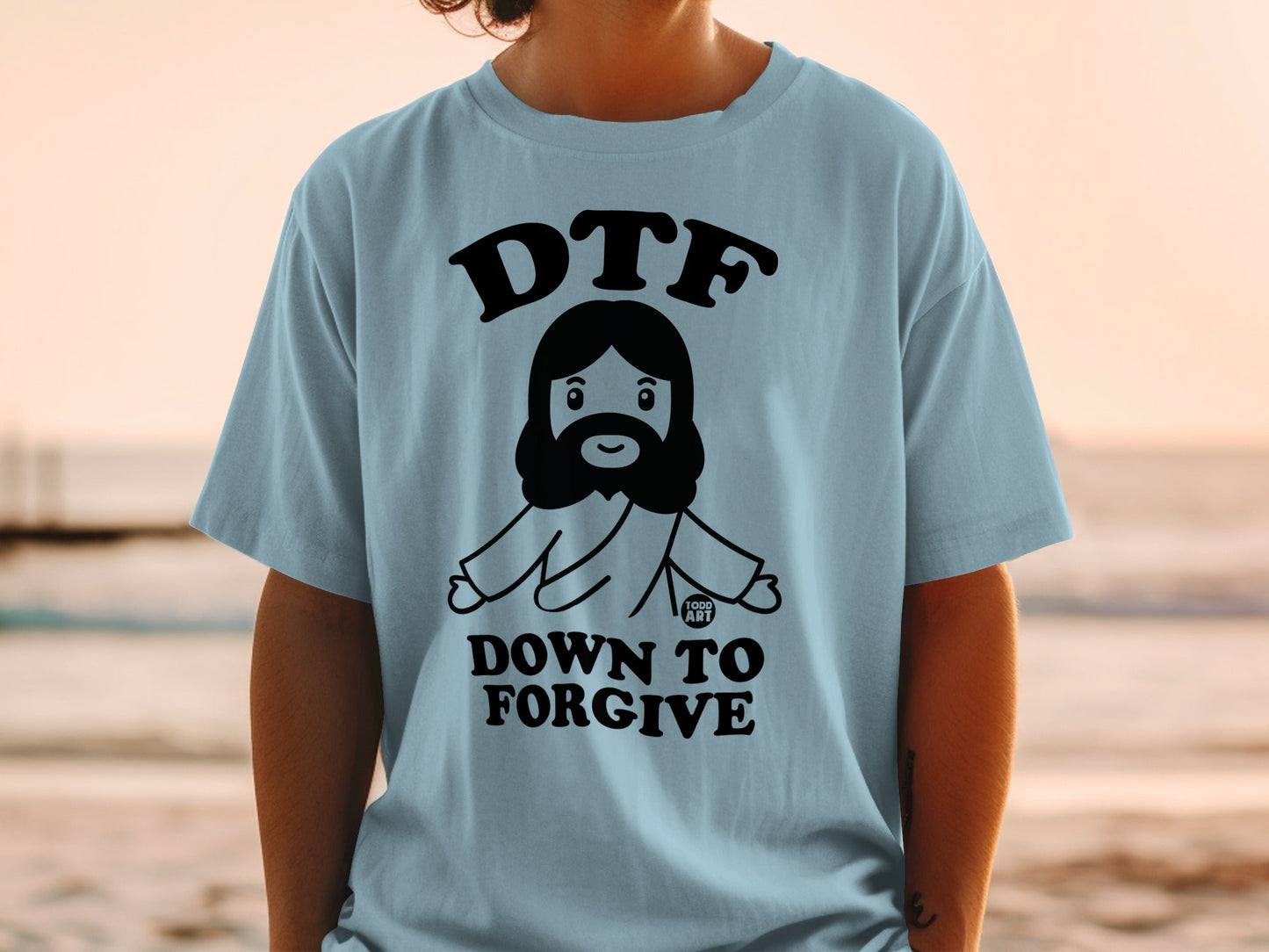 Light blue t-shirt with a cartoon Jesus and the text "DTF DOWN TO FORGIVE".