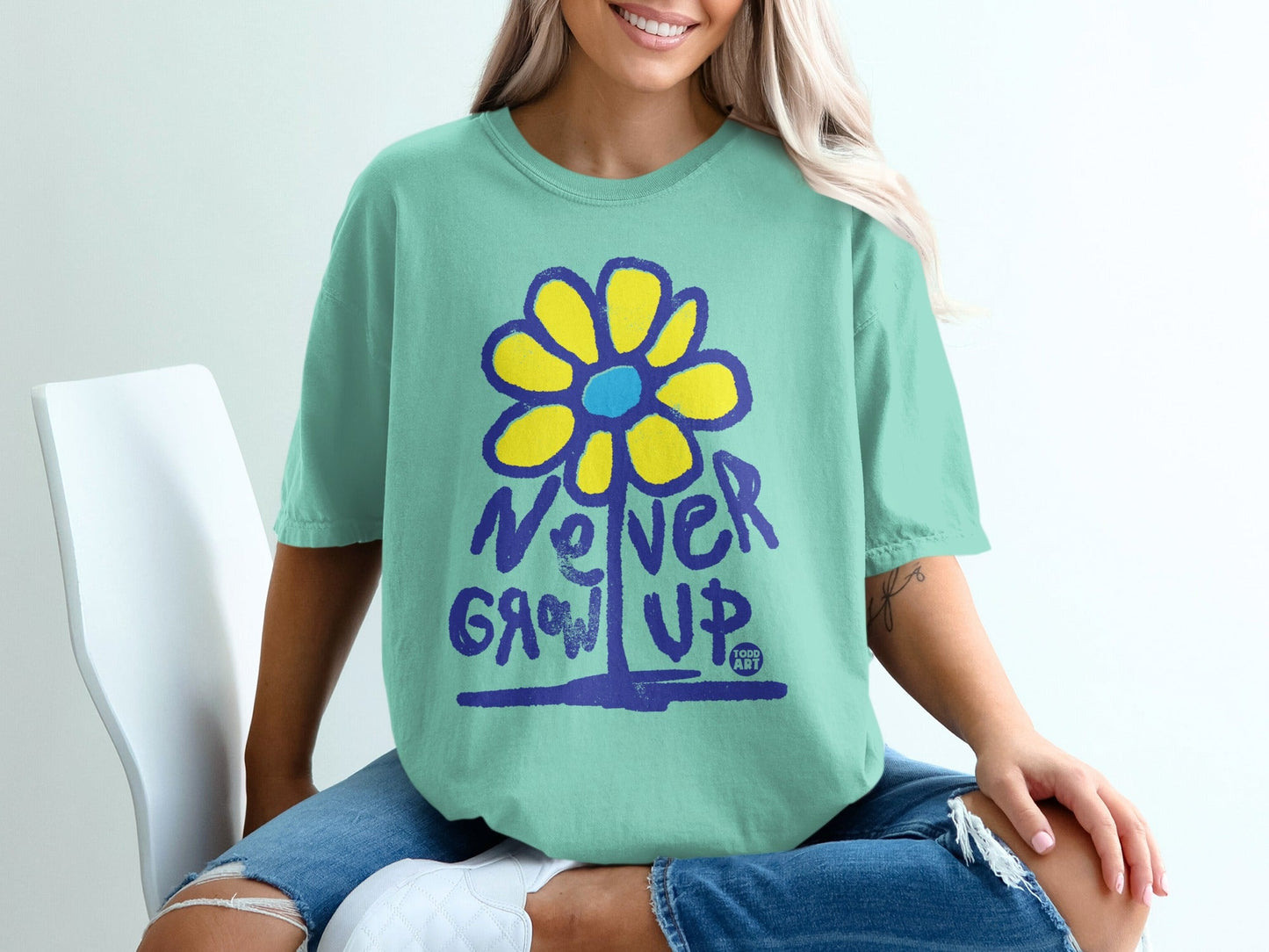 Teal t-shirt with yellow flower graphic and "Never Grow Up" text.