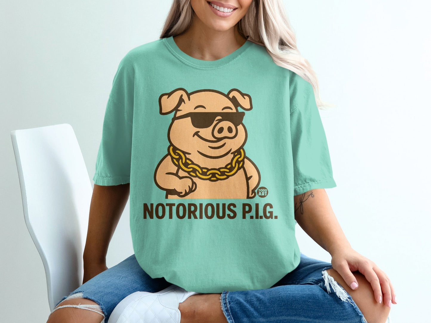 Teal t-shirt with a cartoon pig wearing sunglasses and a gold chain, "Notorious P.I.G." text.